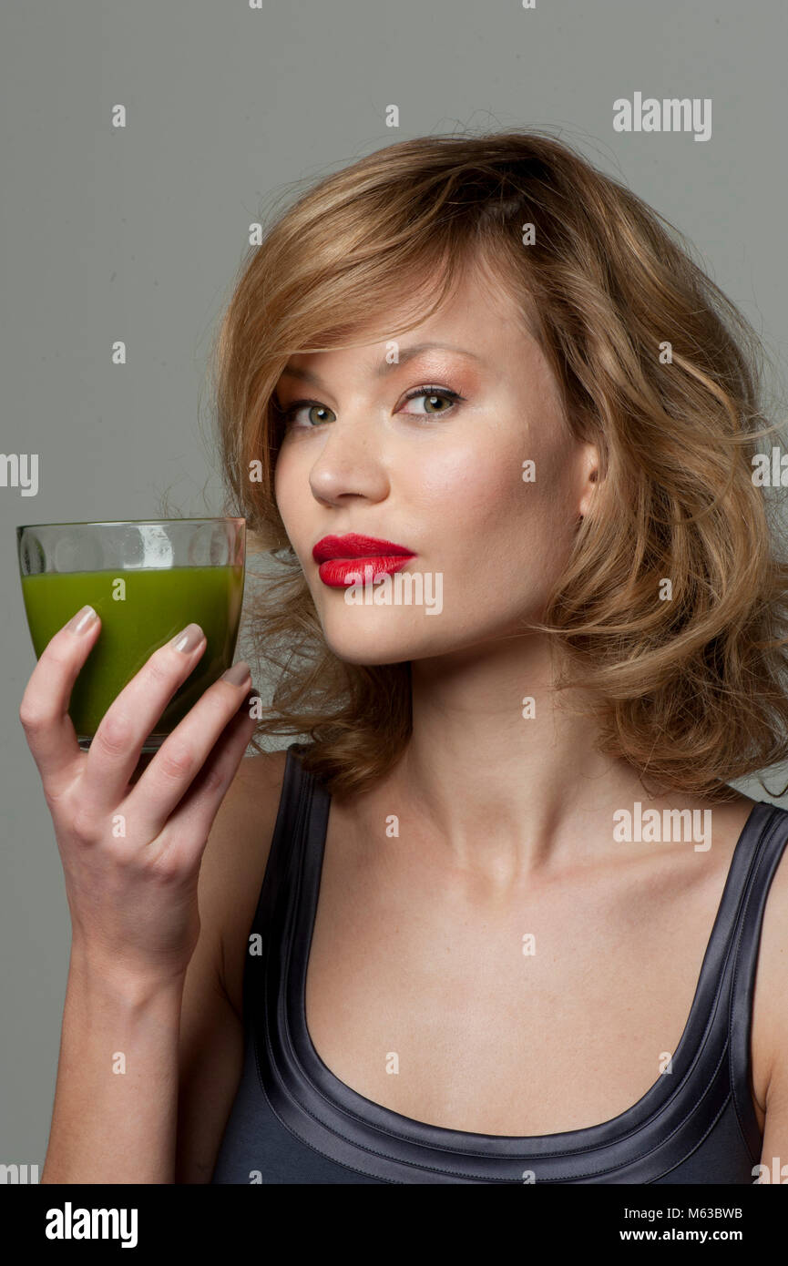 Woman holding a glass of green juice Stock Photo