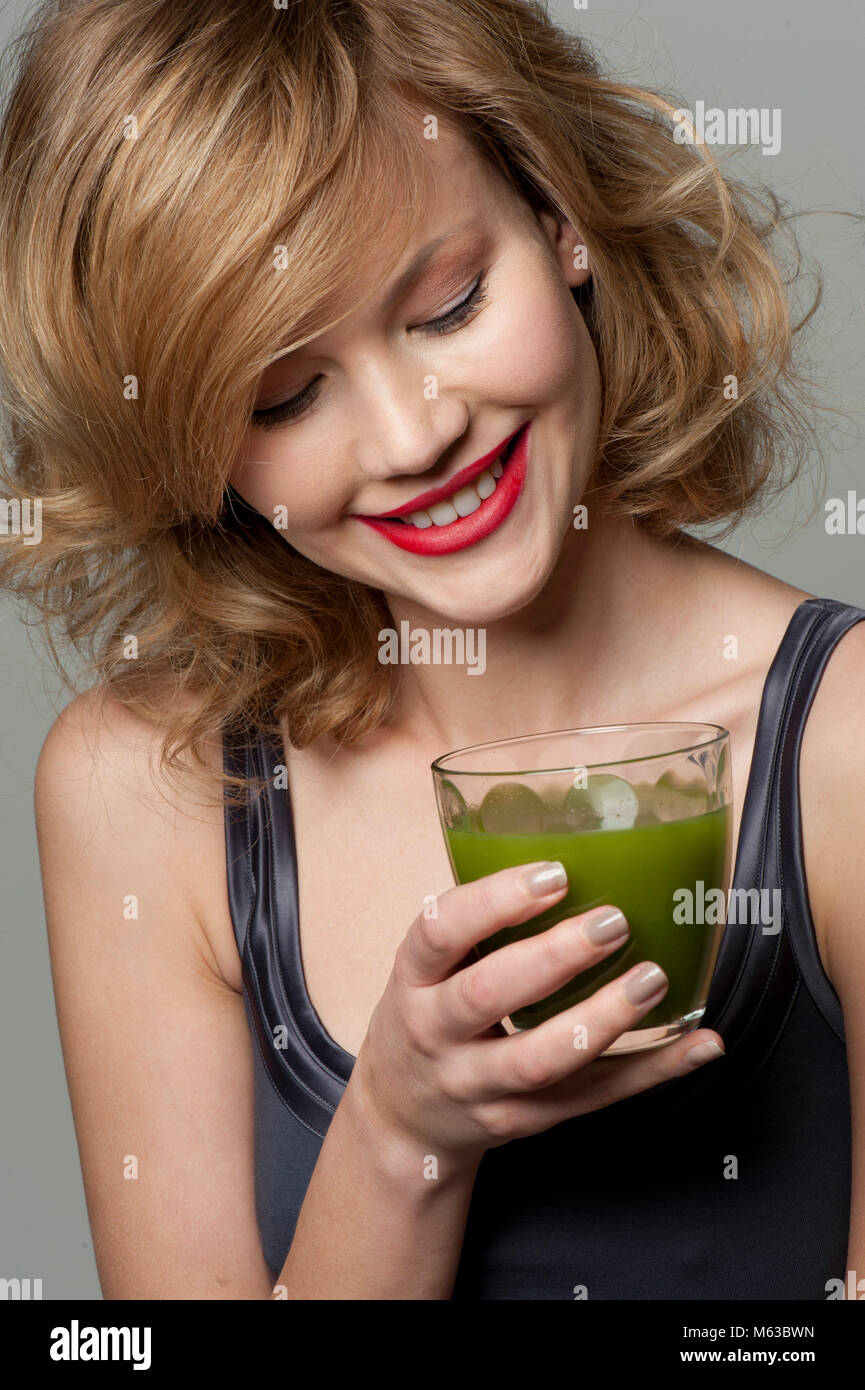 Happy woman with glass of green juice Stock Photo