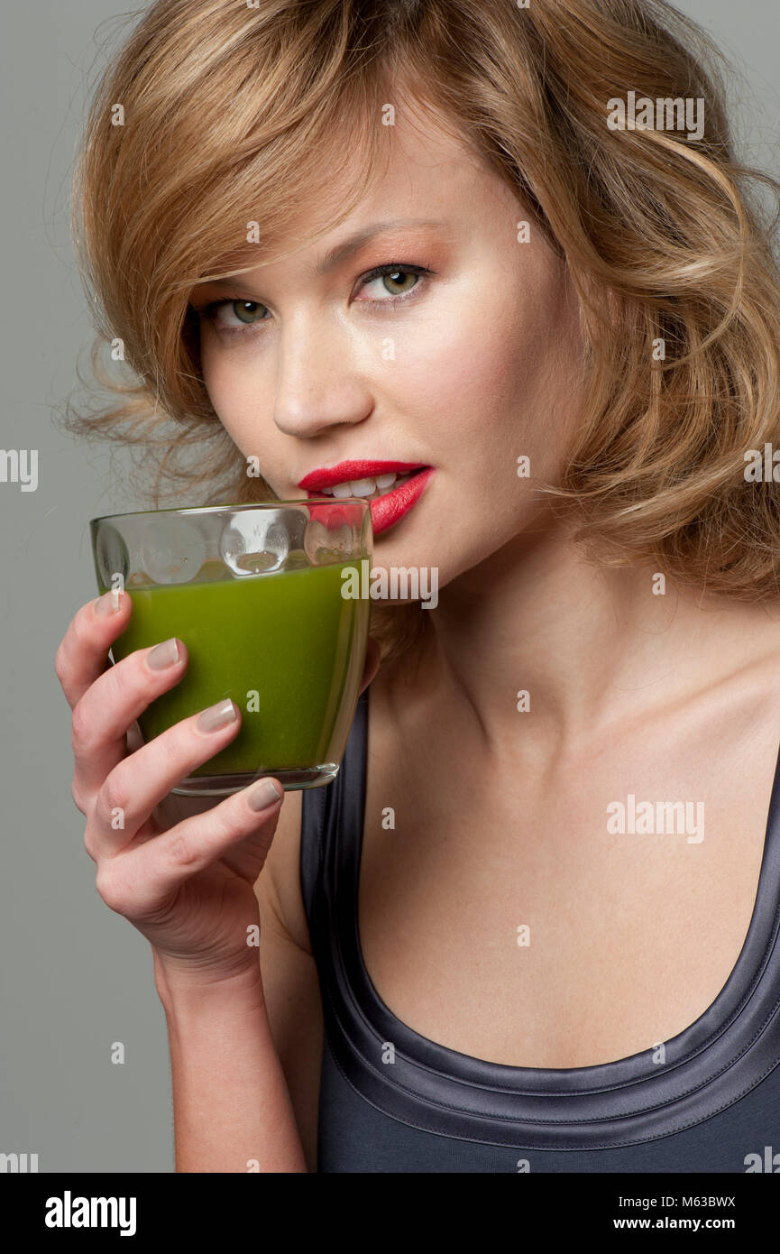 Woman drinking green juice from a glass Stock Photo