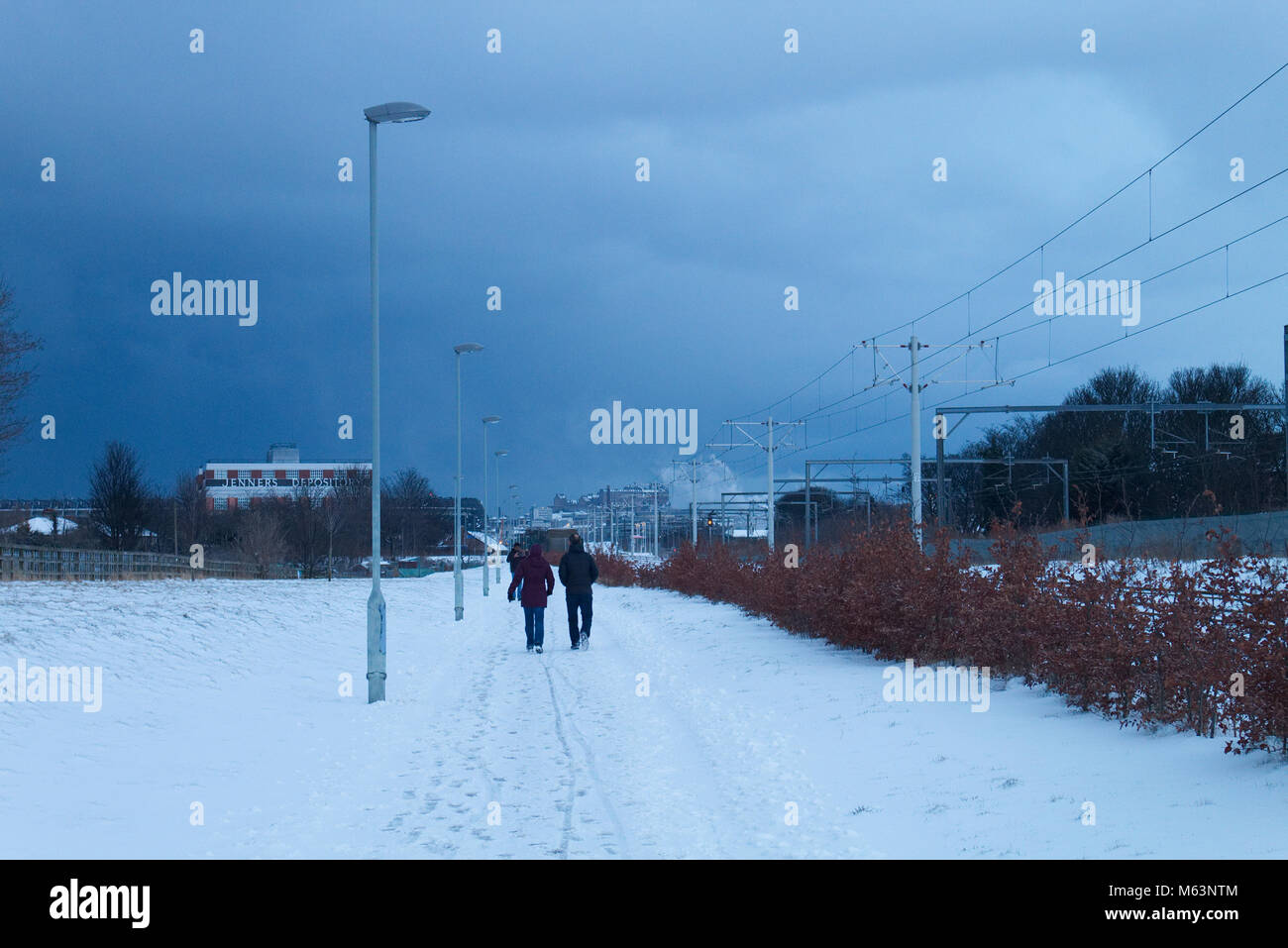 Edinburgh, Scotland, UK. 28th February, 2018. A couple is walking on the path adjacent to the Edinburgh Tram Line as the snow storm 'the Beast from the East' is moving into Edinburgh.  Credit: Iscotlanda/Alamy Live News Stock Photo