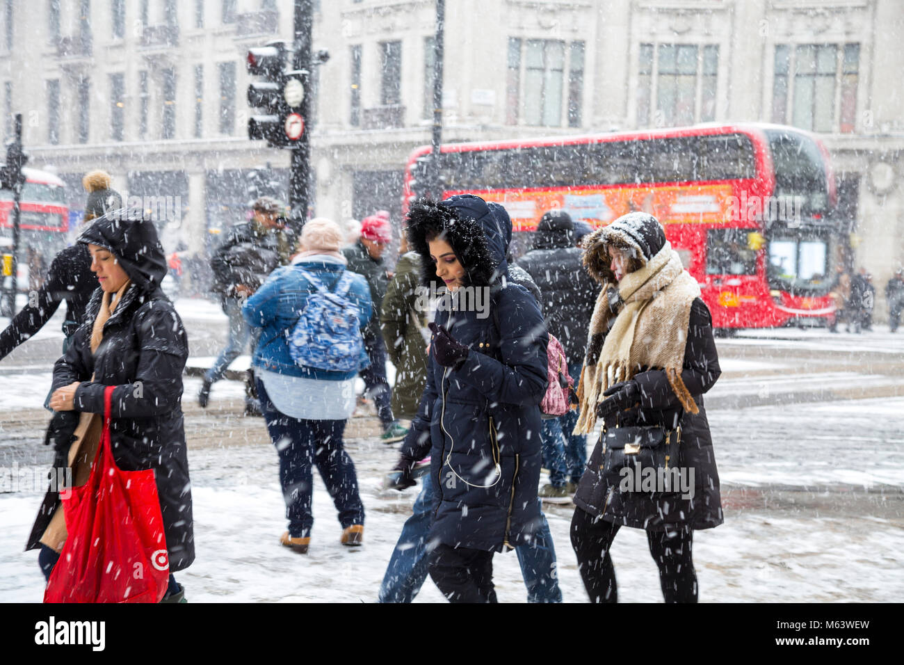 London, UK. 28th Feb, 2018. UK Weather: Heavy snow caused severe early delays for millions of London commuters, people walking around the centre of the capital (Oxford Circus) shielding from wind and snow Credit: Nathaniel Noir/Alamy Live News Stock Photo