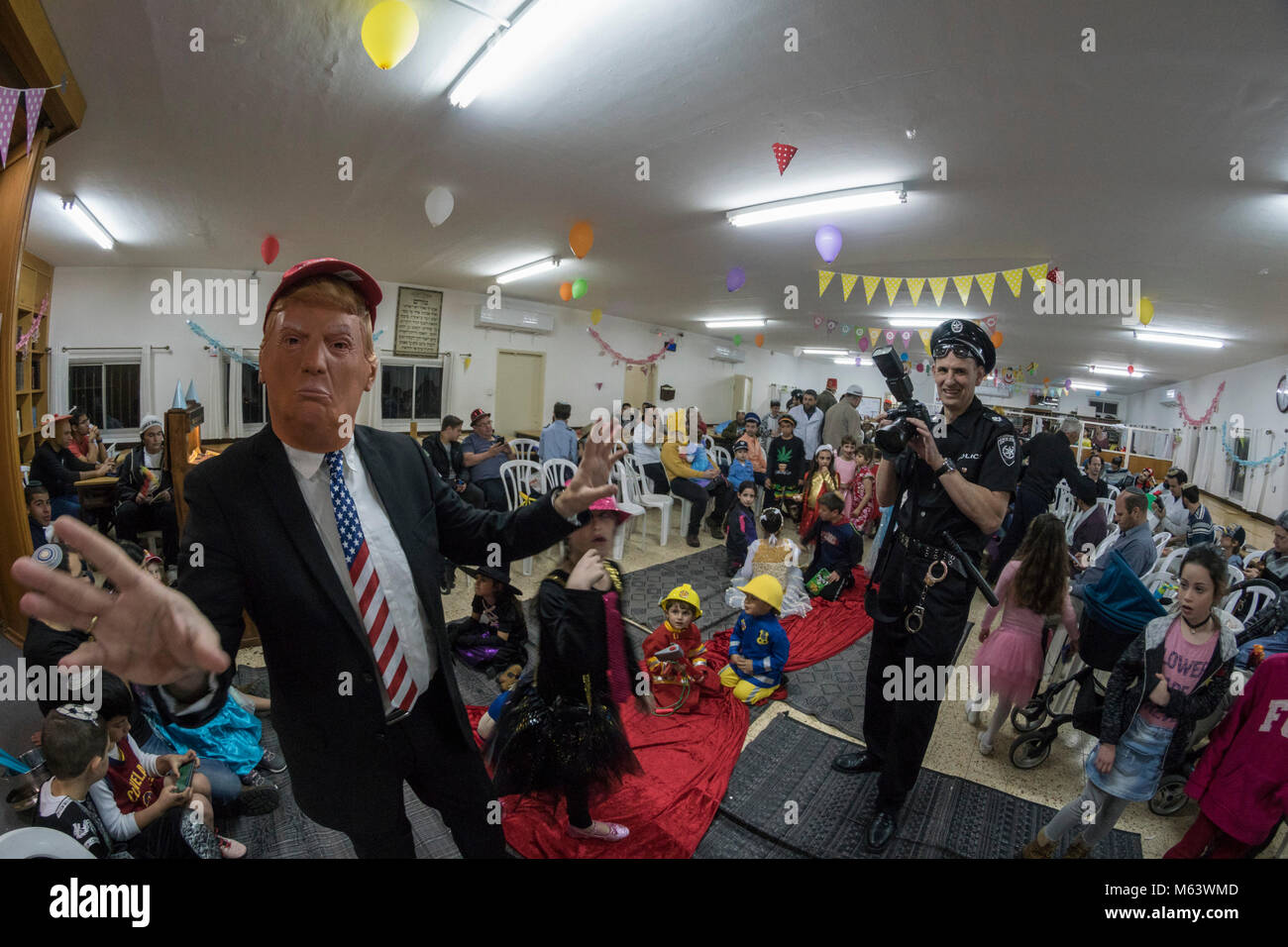 Elkana, Israel. 28th Feb, 2018. Purim holiday celebrations, Elkana, Israel. February 28th, 2018. A man with a Trump Mask and other people in costumes celebrate the Jewish holiday of Purim. In this holiday Jews traditionaly dress in costumes, read the scroll of Esther, a story about an anti-jewish failed plot in ancient Persia, and make a racket whenever the name of Haman, the main antagonist, is mentioned. Credit: Yagil Henkin/Alamy Live News Stock Photo