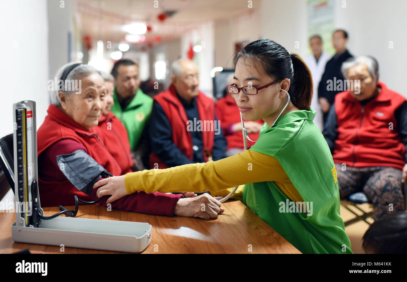 Anping, China's Hebei Province. 28th Feb, 2018. A volunteer measures blood pressure for an old woman at the Chunhuiyuan Beadhouse in Anping County, north China's Hebei Province, Feb. 28, 2018. A volunteer service activity was held here to greet the upcoming Lantern Festival, which falls on March 2 this year. Credit: Zhu Xudong/Xinhua/Alamy Live News Stock Photo