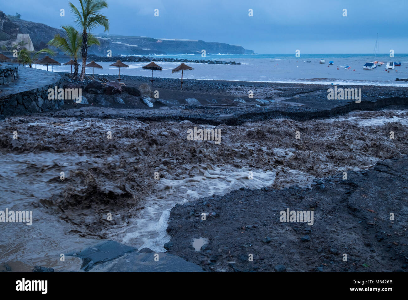 Playa San Juan, Tenerife, 28 February 2018. Floodwaters from heavy rains overnight wash away the beach as the water flows down from the mountains.A regular occurrence during the winter months. Canary Islands Spain Stock Photo