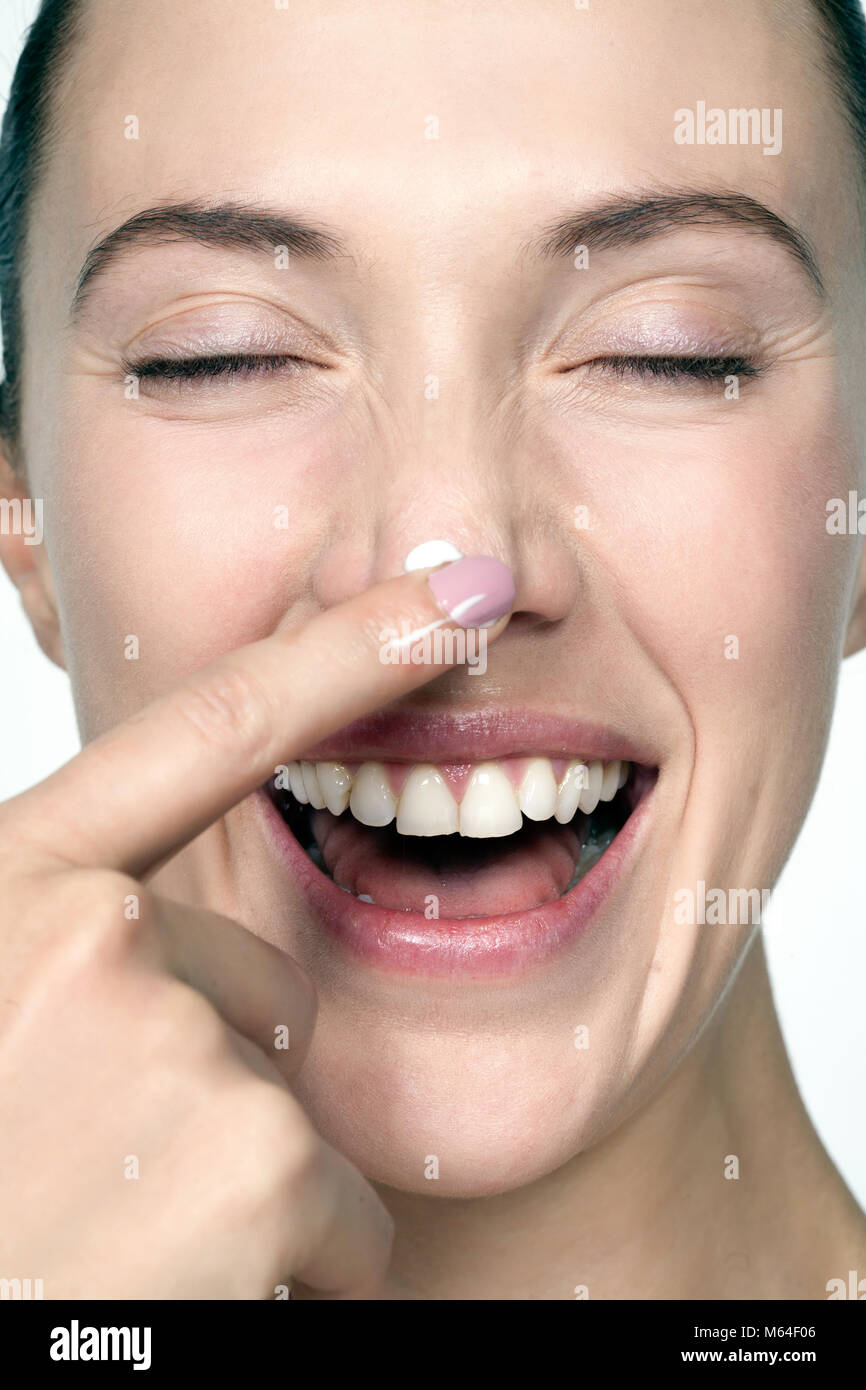 Happy woman applying cream to nose Stock Photo