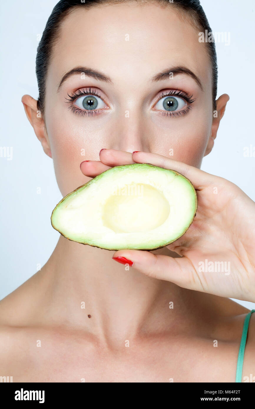 Woman holding avocado half over her mouth Stock Photo