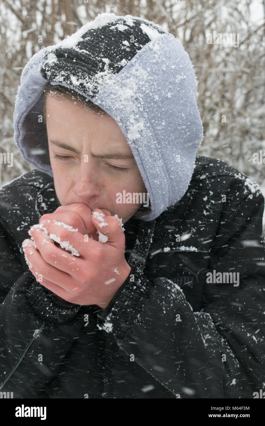 Young adolescent child with freezing cold hands after playing in the snow. Stock Photo