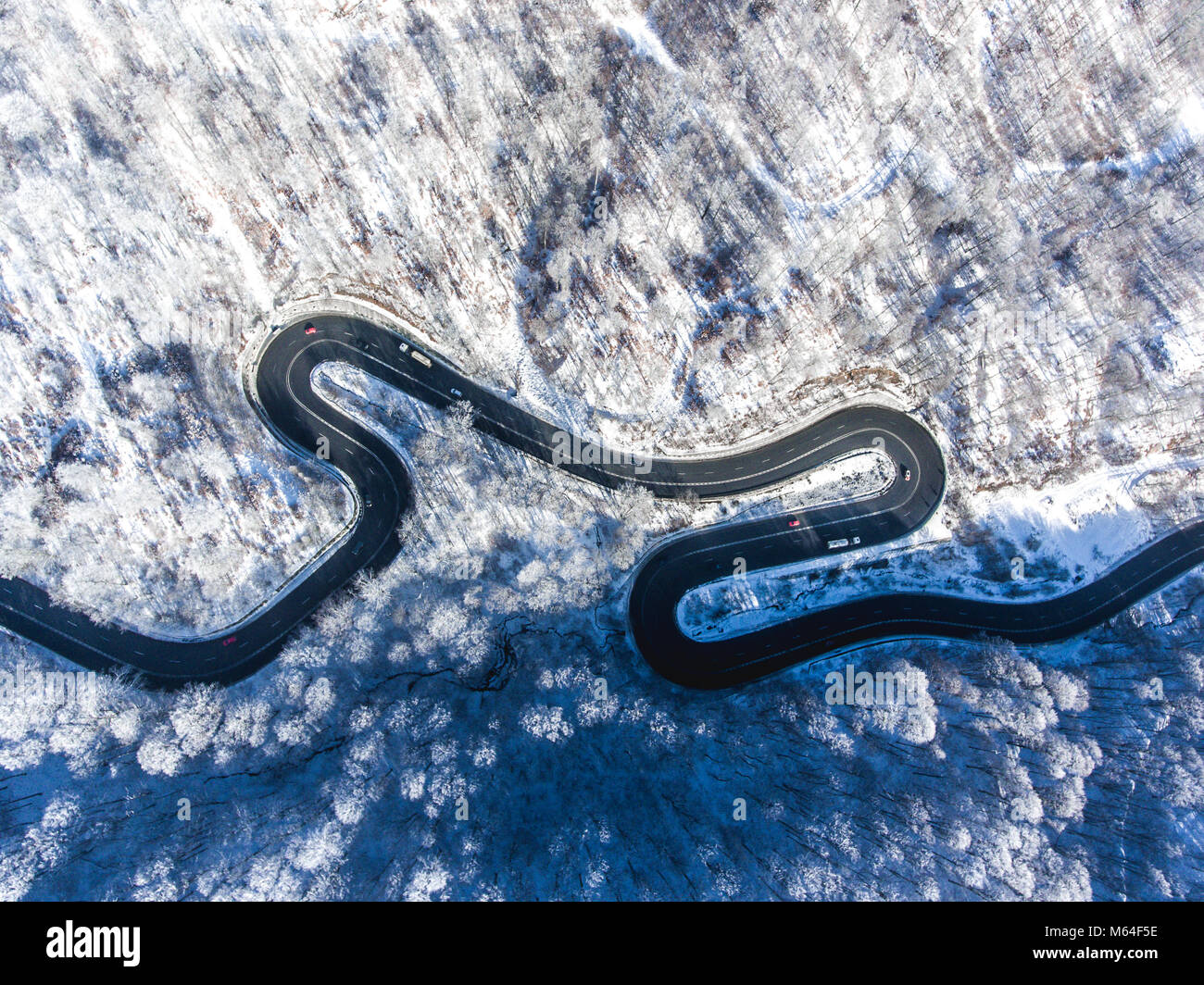 Aerial drone view of a curved winding road through the forest high up ...