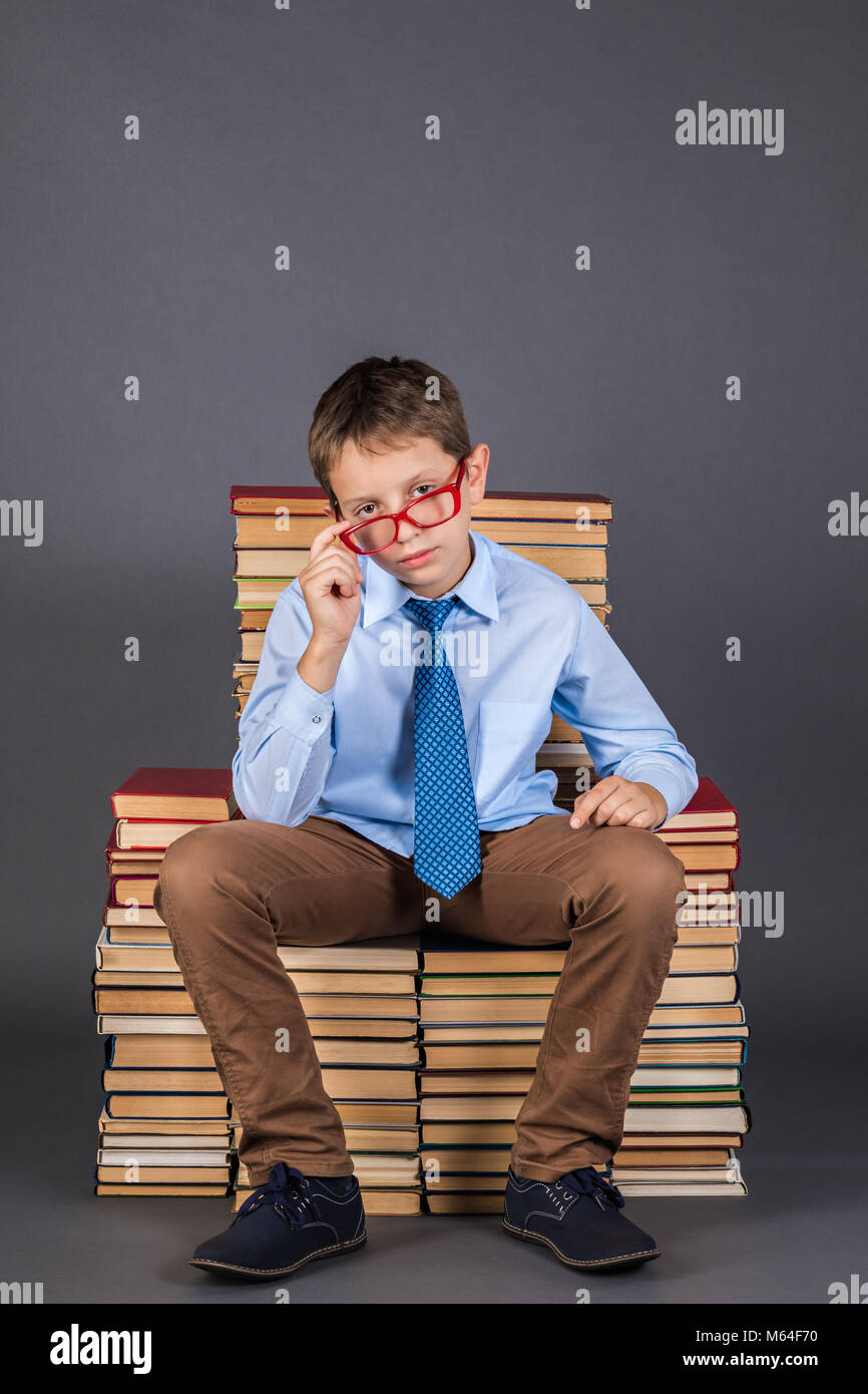 Boy leader sitting on the throne from books, education funny idea Stock Photo