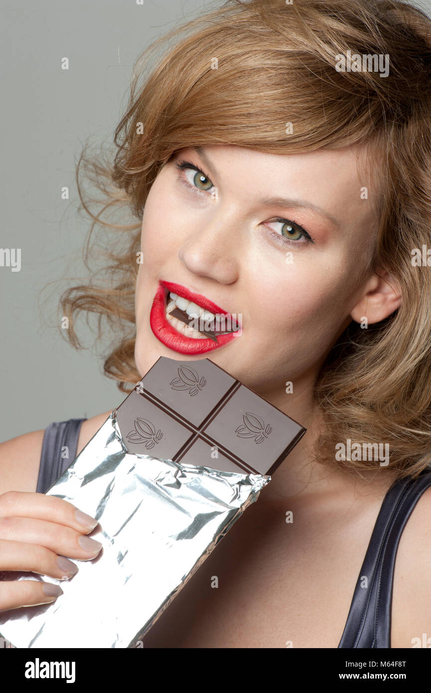 Woman eating bar of dark chocolate Stock Photo