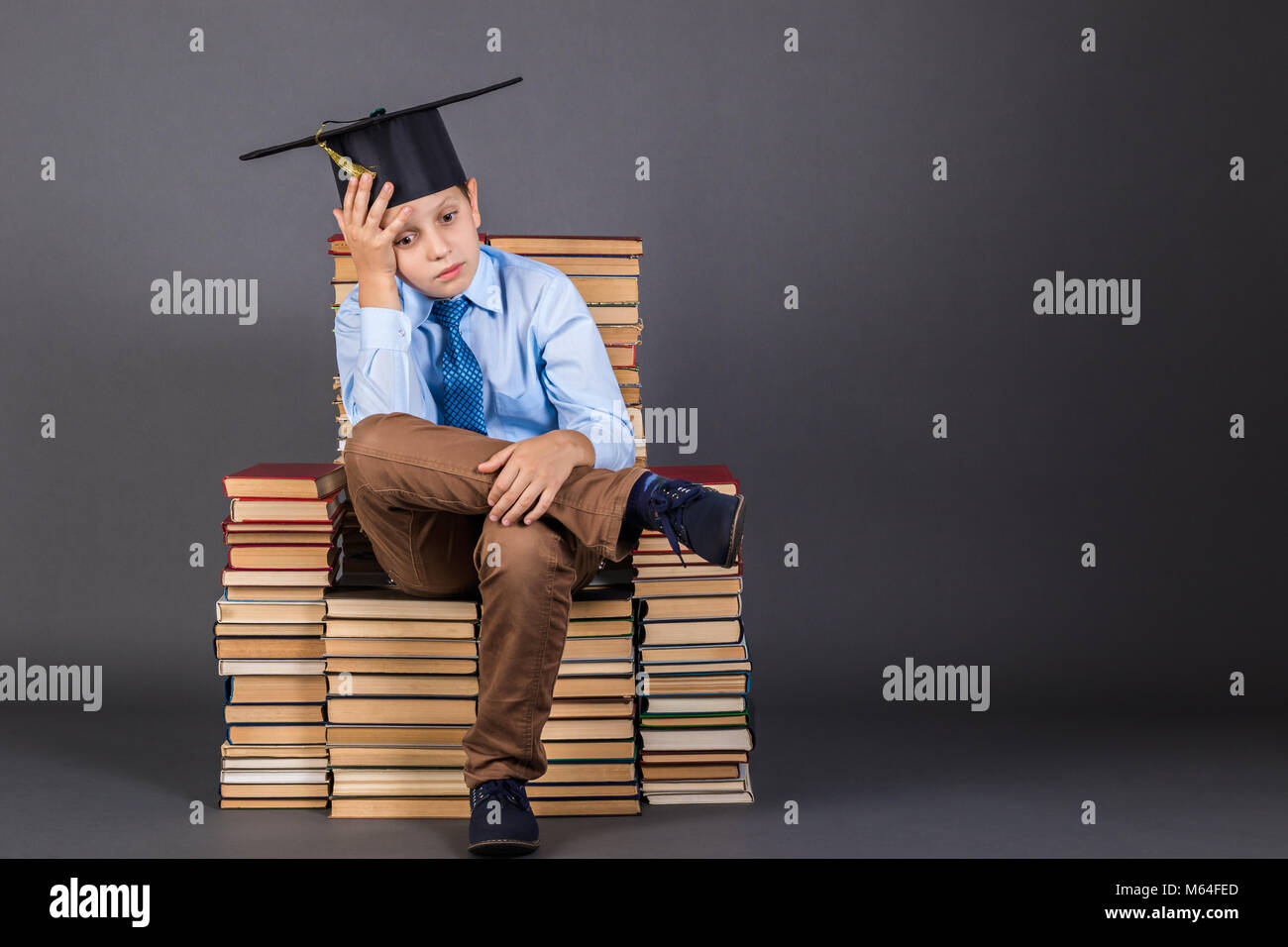 Education concept. Pensive boy sitting on a throne from books Stock Photo