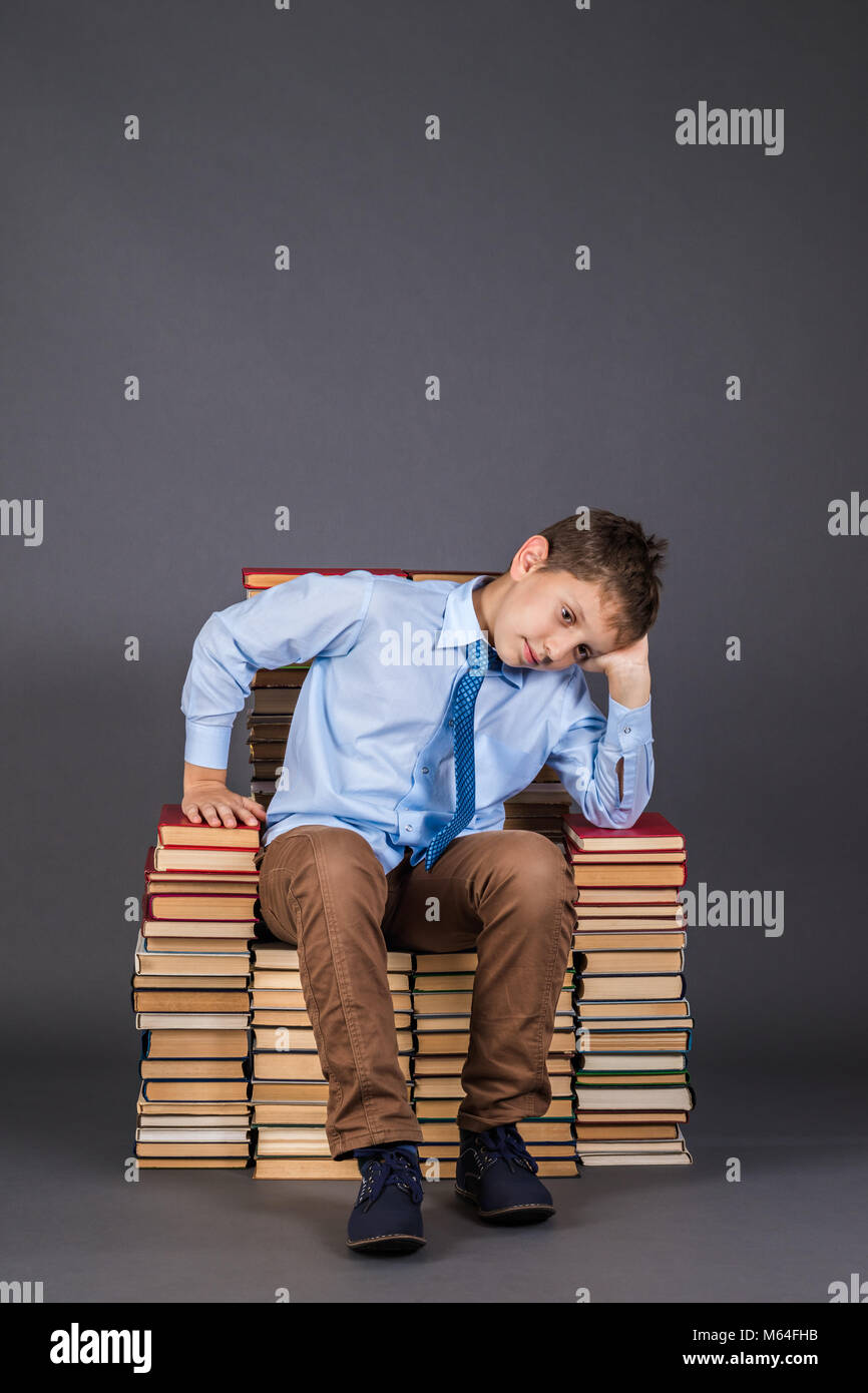 Education concept. Dreaming boy the reader sitting on a throne from books Stock Photo