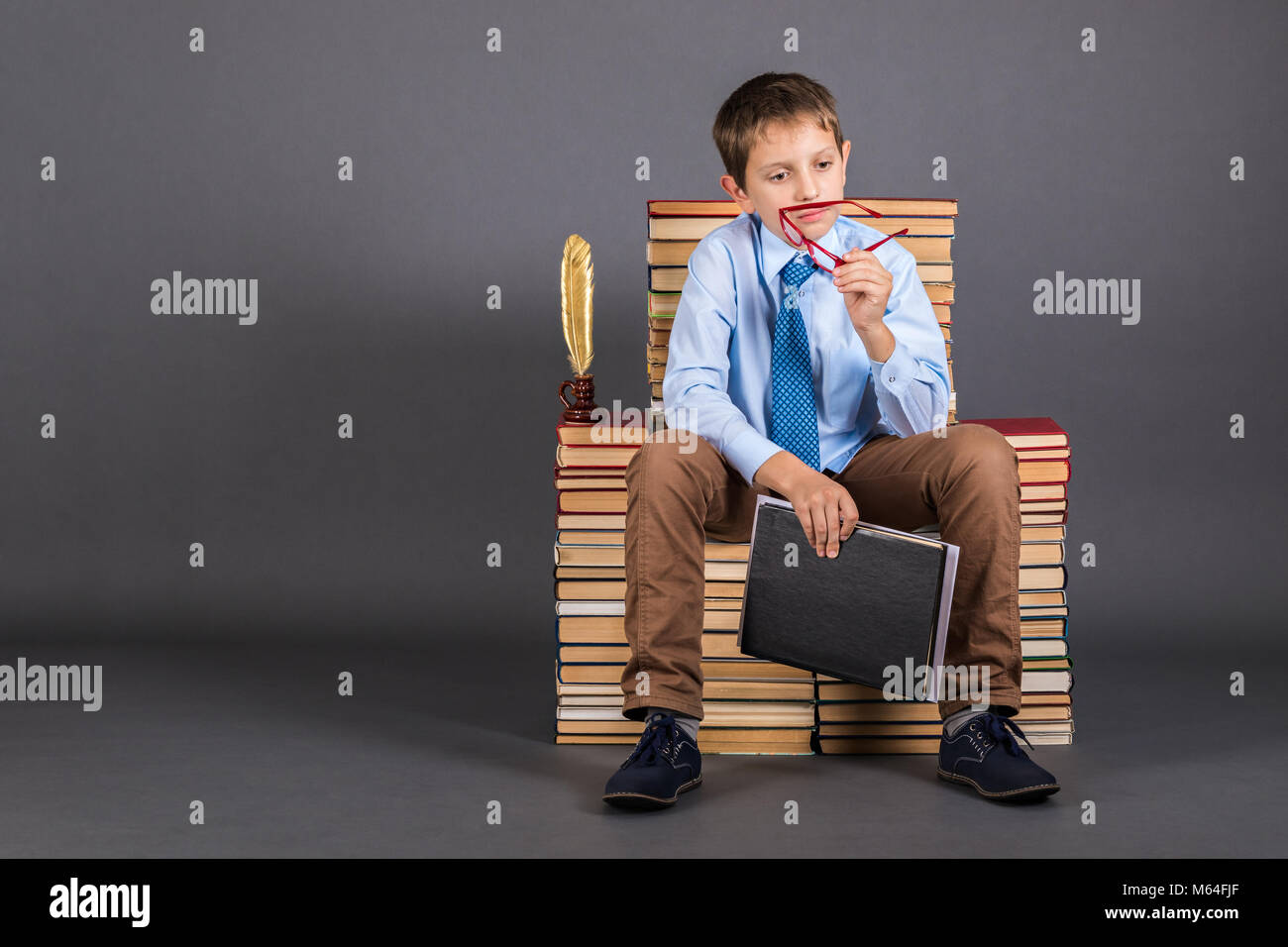 Education idea. A boy sitting on a throne from books plans his daily routine Stock Photo