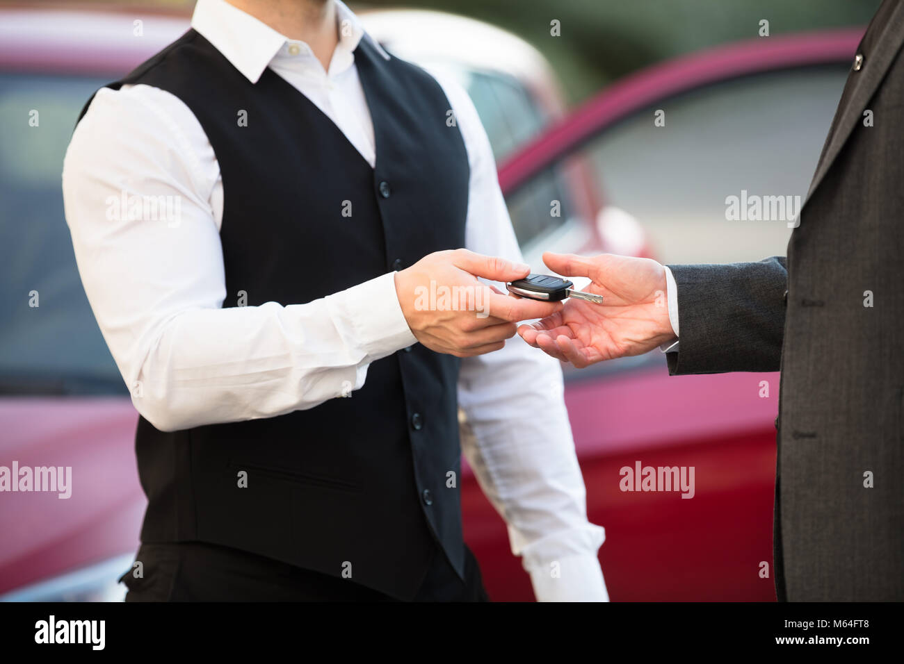 Close-up Of Valet's Hand Giving Car Key To Businessperson Stock Photo