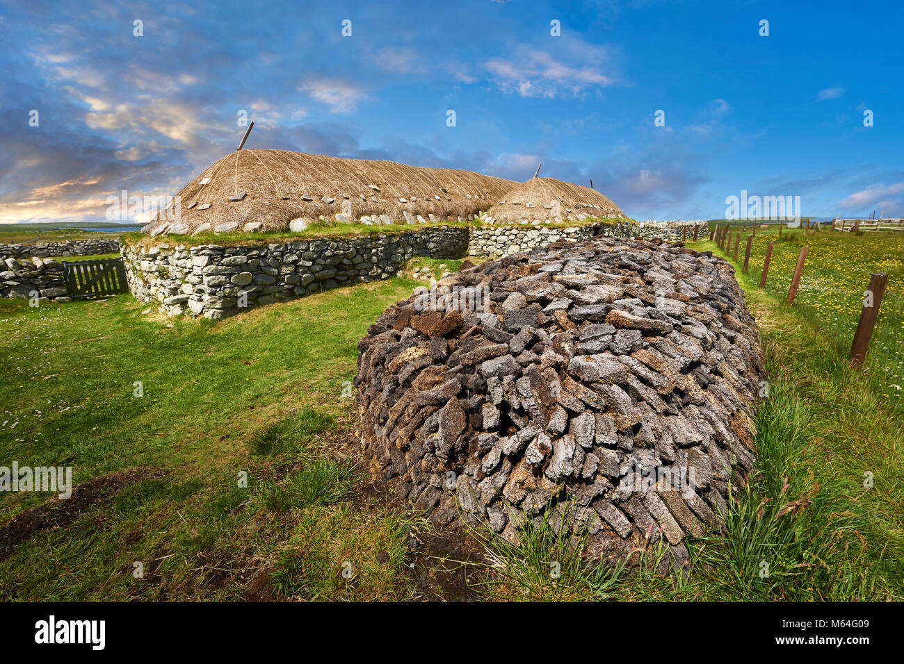 Picture & image peat pile oustide the exterior with stone walls and thatched roof of The historic Blackhouse, 24 Arnol, Bragar, Isle of Lewis, Scotlan Stock Photo