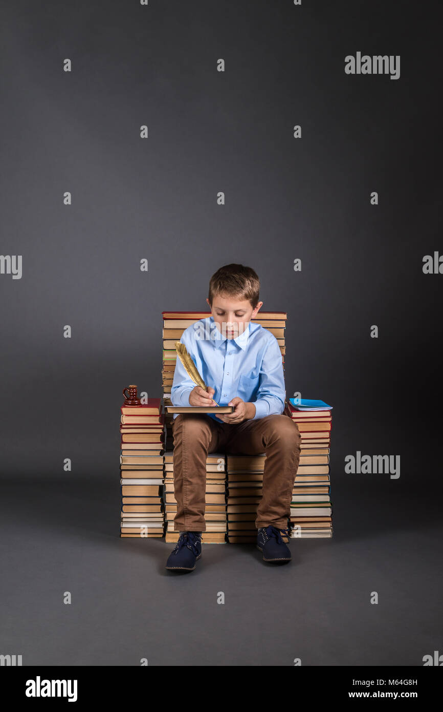 Education concept. A boy with quill pen sits on a throne of books Stock Photo