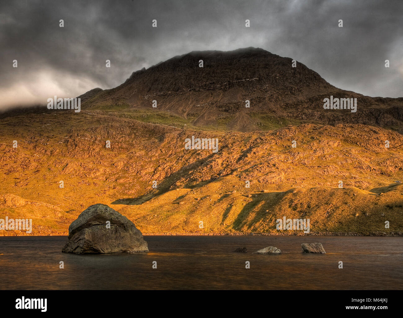 Crib Goch mountain at sunrise under heavy clouds, Snowdonia, Wales Stock Photo