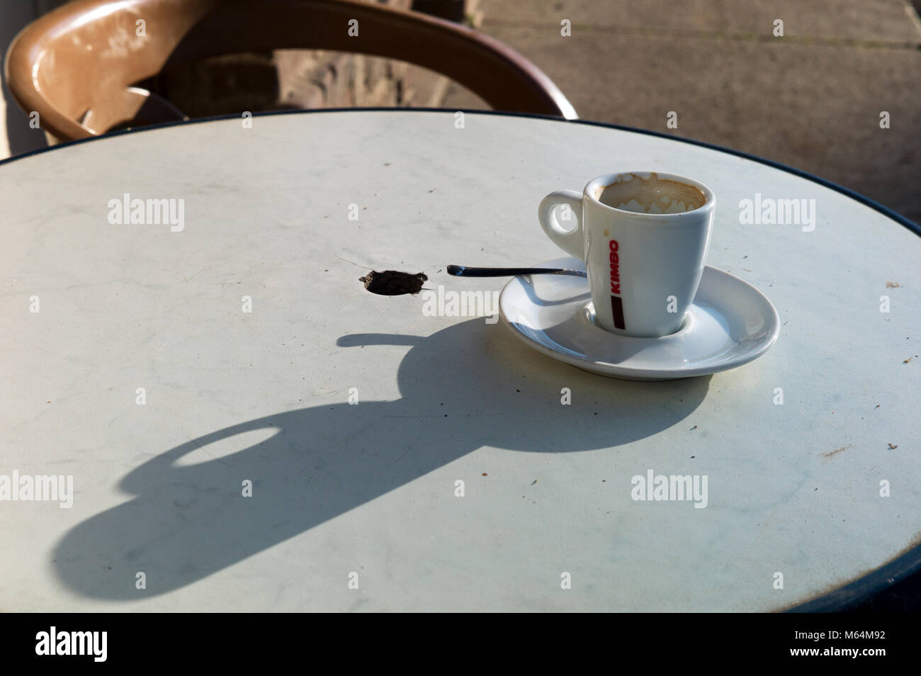Empty coffee cup on bistro table, sunlight and strong shadow Stock Photo