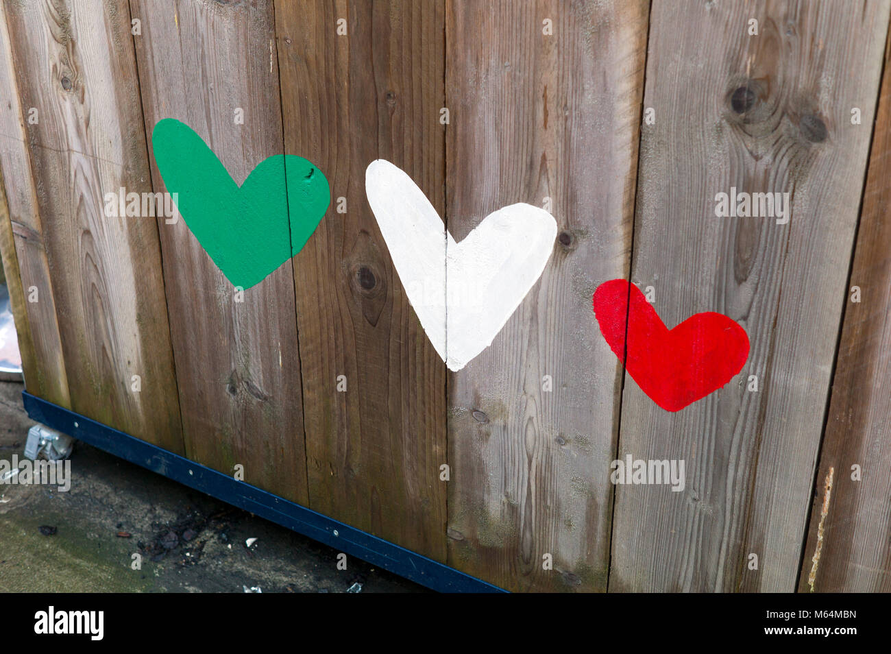 Painted red green and white hearts on wooden fence Stock Photo