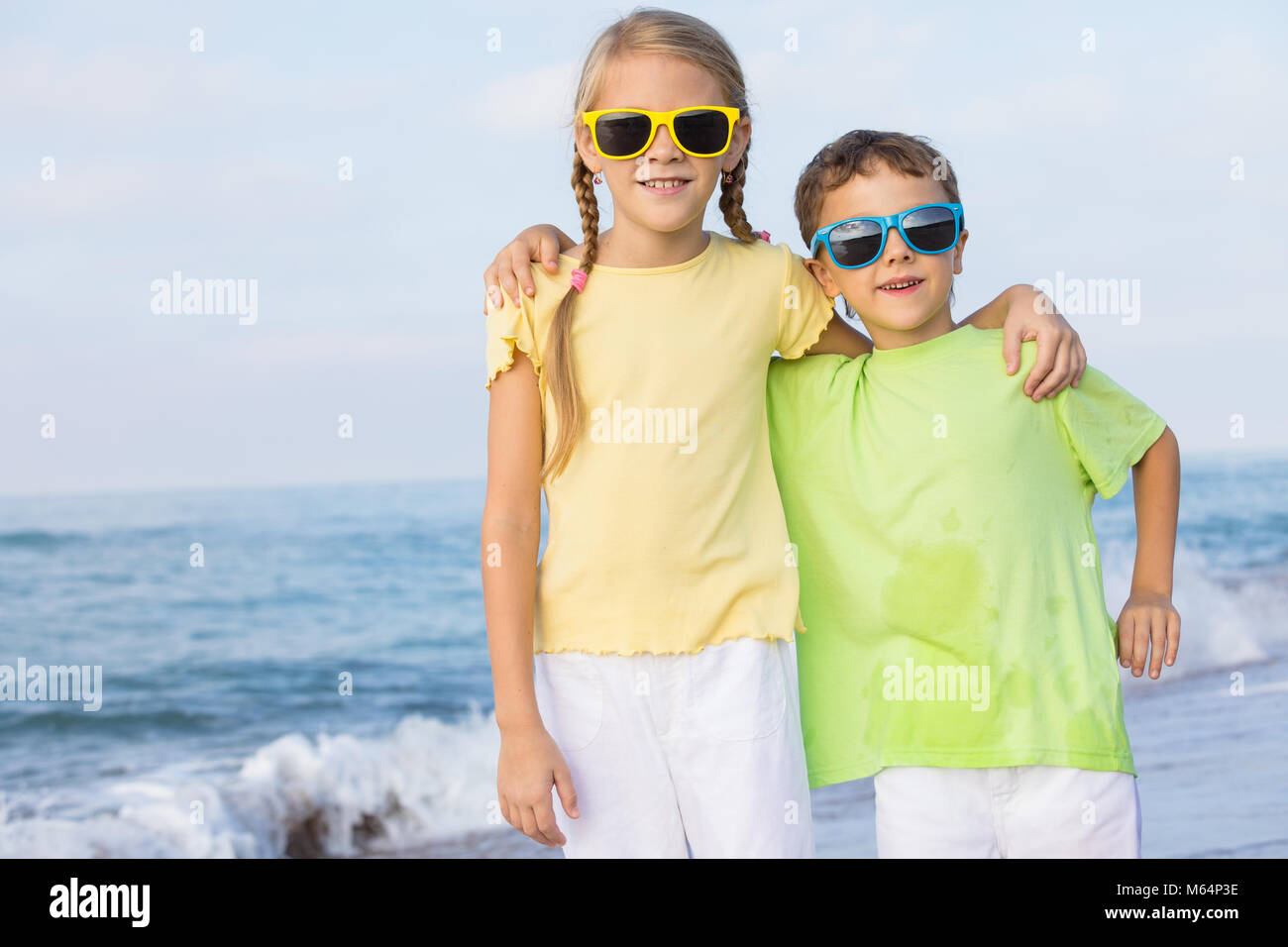 Two happy little children playing on the beach at the day time.  Kids having fun outdoors. Concept of summer vacation and friendly family. Stock Photo