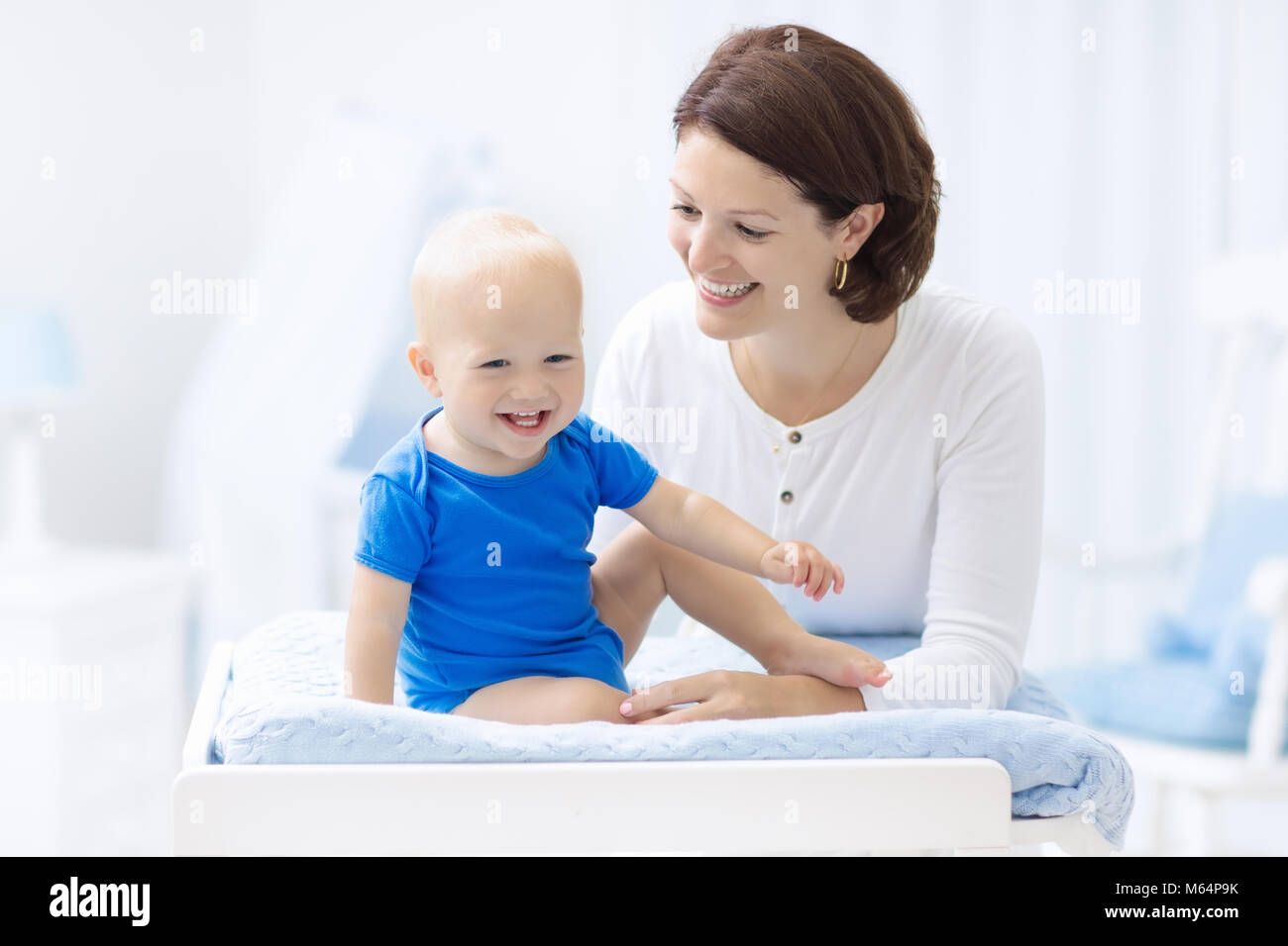 Mother and baby in diaper on changing table. Mom changing nappy on baby boy. Kids nursery