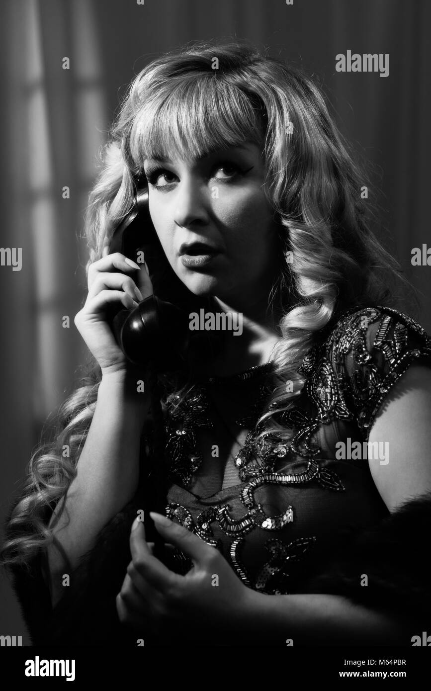 Film Noir style black and white image of woman on a vintage telephone Stock Photo