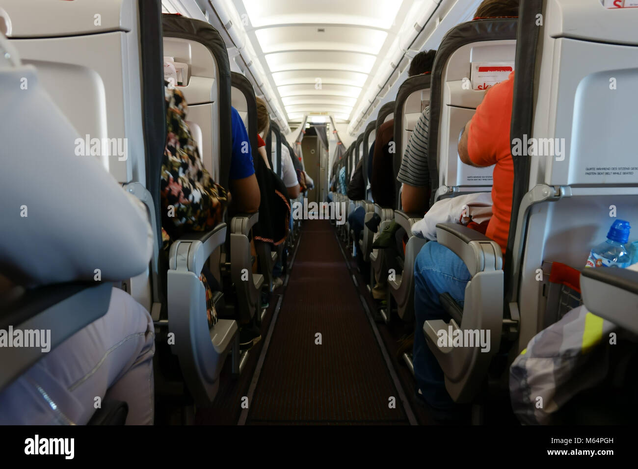 Passenger cabin in flight with people. Economy class. View from the path between rows of aircraft Stock Photo