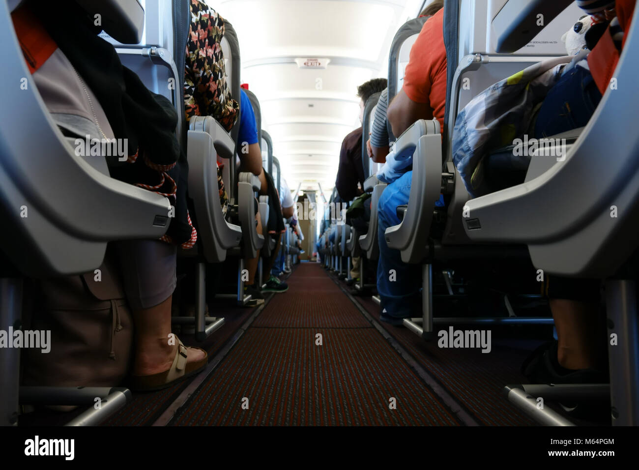 Passenger cabin in flight with people. Economy class. View from floor. Stock Photo