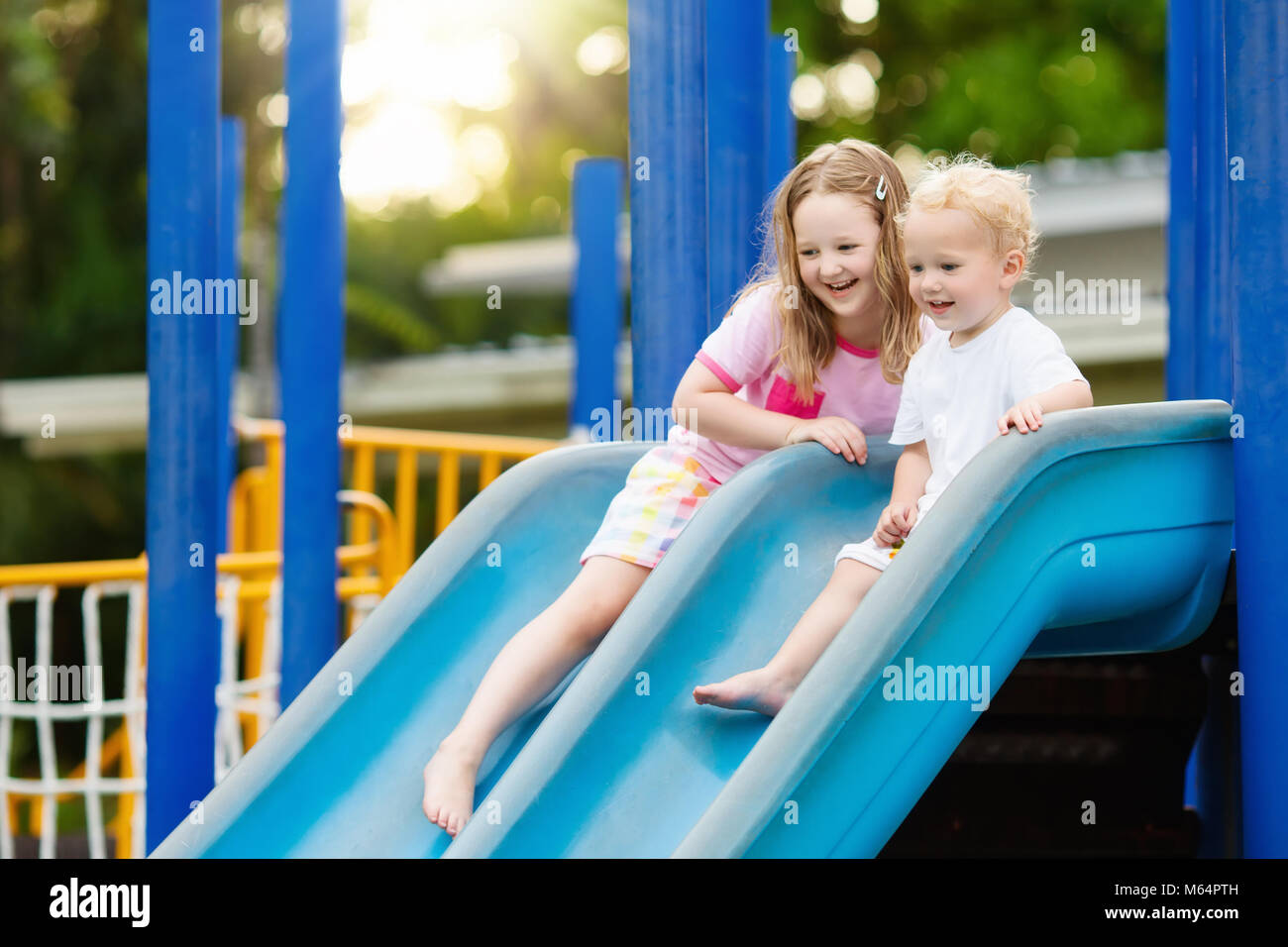 Kids climbing and sliding on outdoor playground. Children play in sunny summer park. Activity and amusement center in kindergarten or school yard. Chi Stock Photo