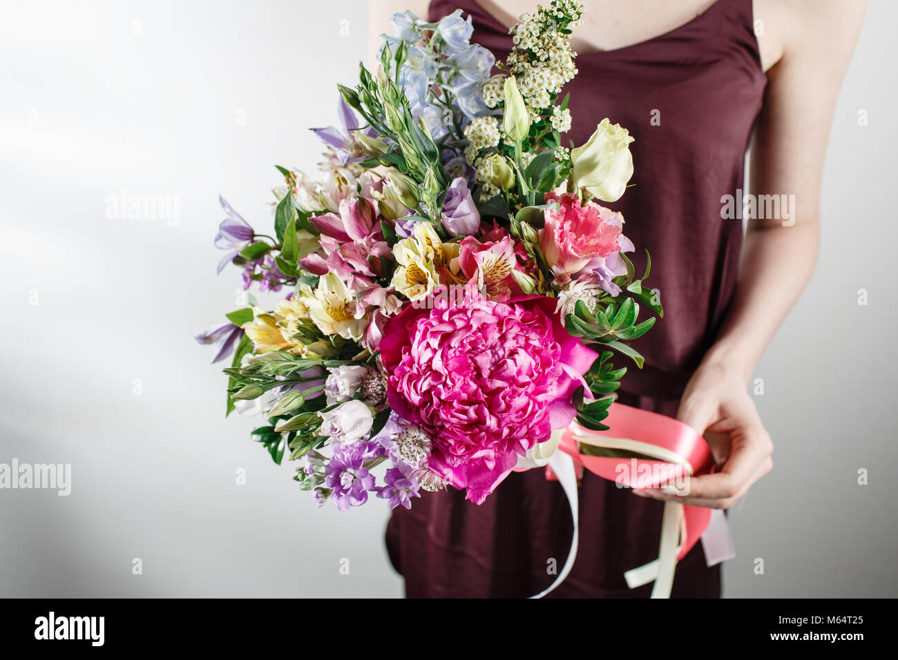 flower composition with peonies. Color pink, green, lavander, blue. beautiful luxury bouquet of mixed flowers in woman hand. the work of the florist at a flower shop Stock Photo