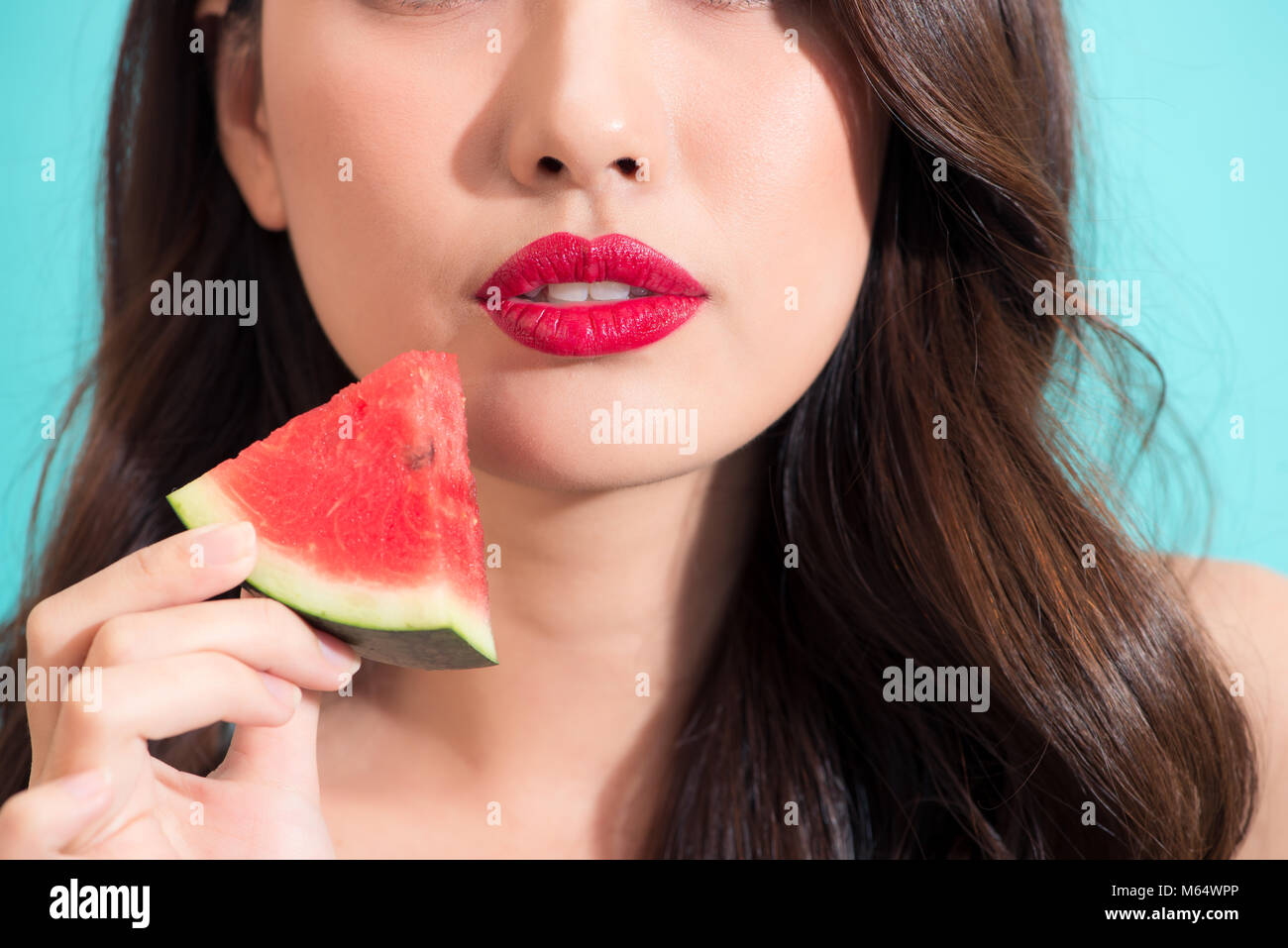 Close-up of a beautiful women holding watermelon slice with red lips. Stock Photo