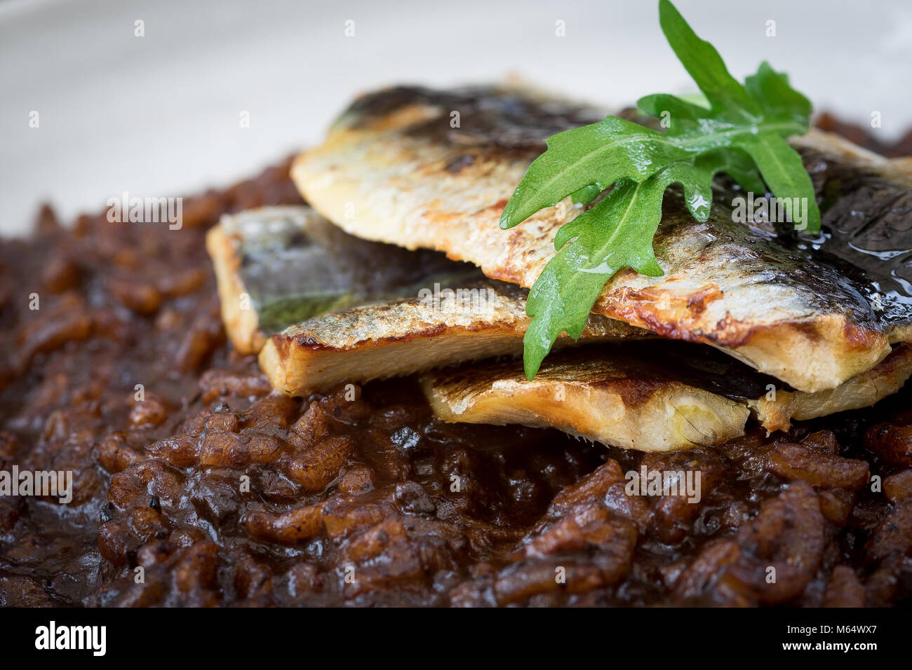 Confit then blowtorched Cornish Sardines, on a black garlic risotto Stock Photo