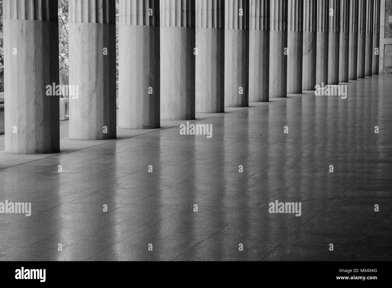 Line of greek columns with reflections on a super shiny floor and no people in monochrome Stock Photo
