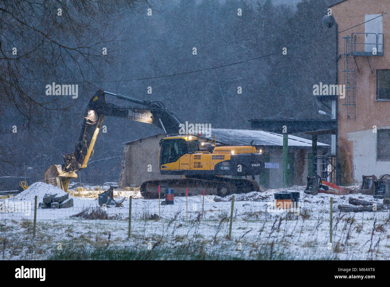 FLODA, SWEDEN - FEBRUARY 2 2018: Mobile articulated excavator working at building site during snowfall in winter  Model Release: No.  Property release: No. Stock Photo