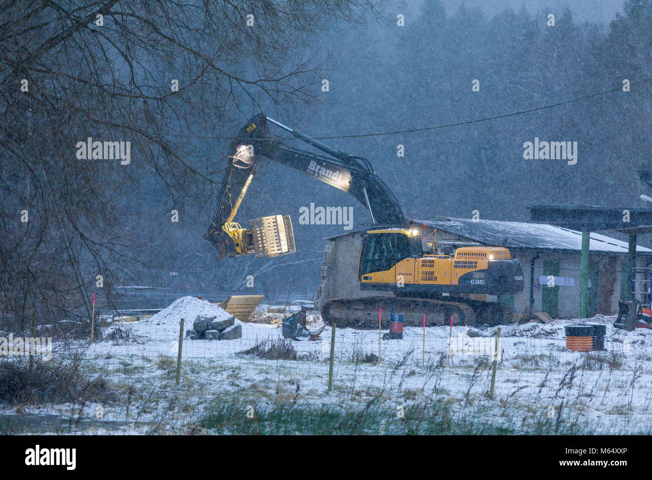 FLODA, SWEDEN - FEBRUARY 2 2018: Mobile articulated excavator working at building site during snowfall in winter  Model Release: No.  Property release: No. Stock Photo