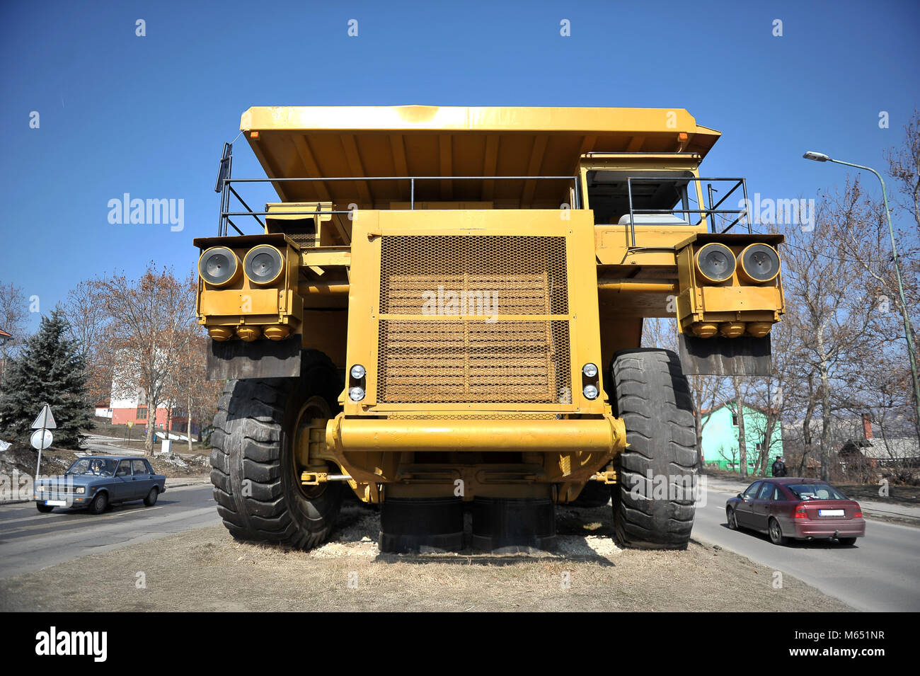 Small cars passing by big yellow mining truck Stock Photo