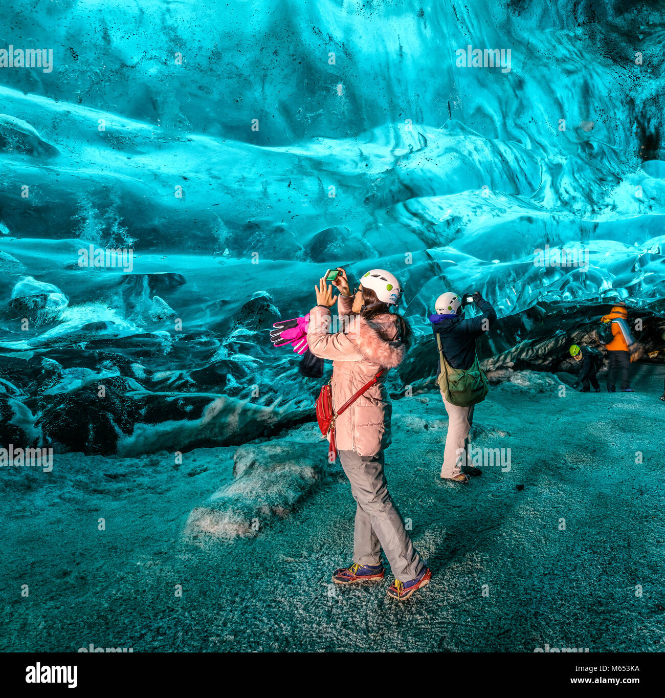 Tourists in The Crystal Cave, Breidamerkurjokull Glacier, Iceland. Emerald Blue Ice and Ash is part of Breidamerkurjokull. Stock Photo