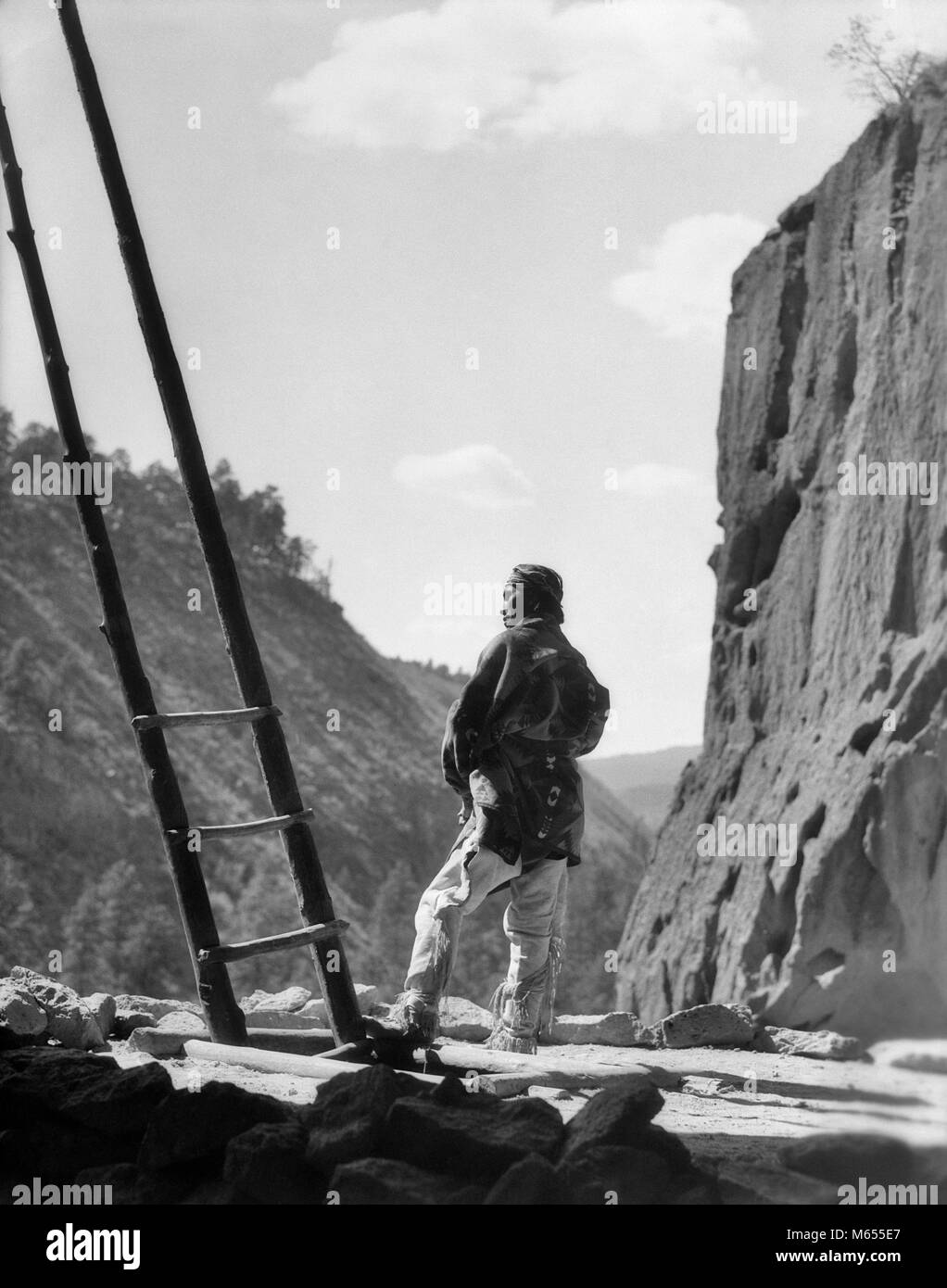 1930s NATIVE AMERICAN INDIAN MAN BY KIVA LADDER FRIJOLES CANYON CEREMONIAL KIVA BANDELIER NATIONAL MONUMENT NEW MEXICO USA - a5036 HAR001 HARS PARKS NATIVE AMERICAN PUEBLO NATIONAL PARK MALES MID-ADULT MID-ADULT MAN NATIVE AMERICANS NEW MEXICO NP B&W BANDELIER BLACK AND WHITE CEREMONIAL FRIJOLES KIVA NATIONAL PARKS OLD FASHIONED PERSONS Stock Photo