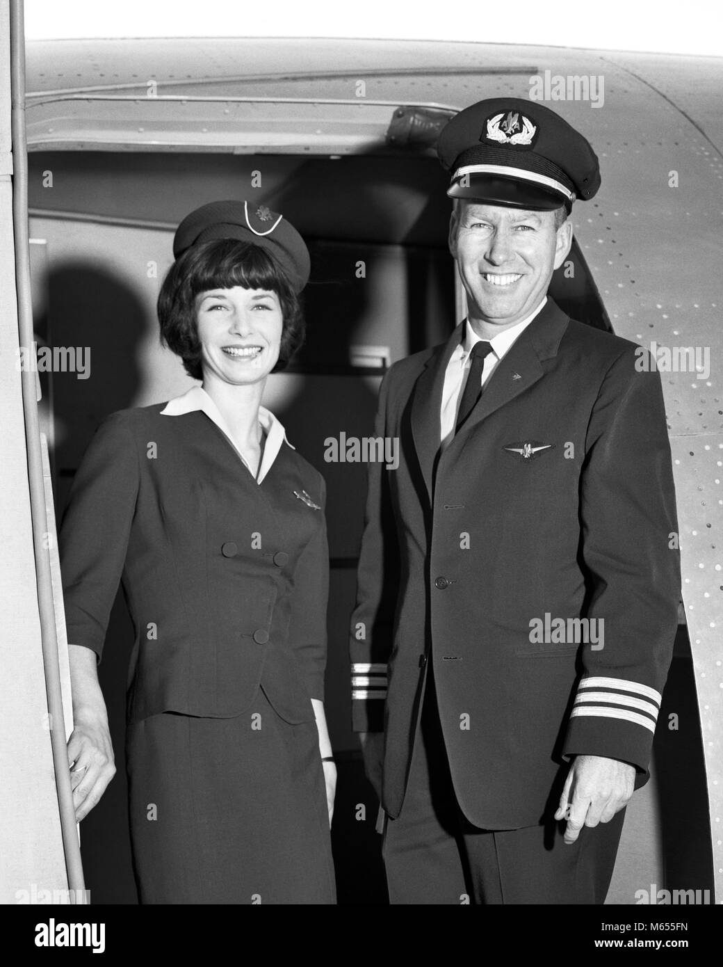1960s MAN CO-PILOT AND WOMAN FLIGHT ATTENDANT STANDING SMILING IN DOOR OF  AIRPLANE LOOKING AT CAMERA - a7297 HAR001 HARS PILOT OLD TIME OLD FASHION  AIRCRAFT BOARDING STYLE WELCOME YOUNG ADULT SAFETY