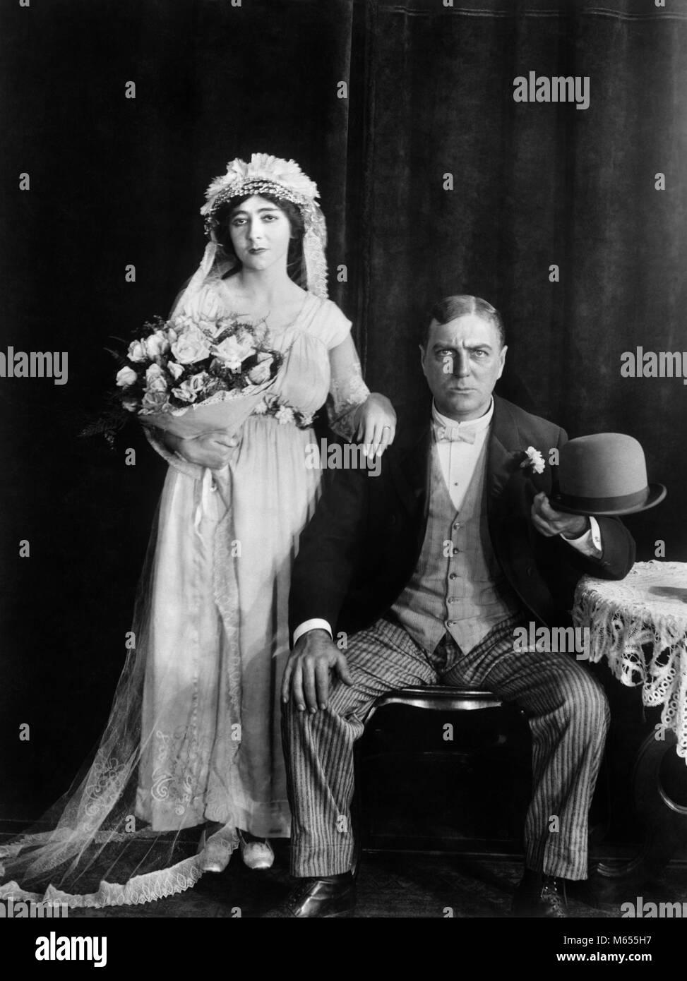 1890s 1910s WEDDING PORTRAIT SERIOUS BRIDE AND GROOM LOOKING AT CAMERA SILENT MOVIE STILL - asm02687 CAM001 HARS COPY SPACE FULL-LENGTH MARRIAGE 1900s COUPLES INDOORS CEREMONY EXPRESSIONS NOSTALGIA HUSBAND AND WIFE TOGETHERNESS EYE CONTACT 25-30 YEARS 30-35 YEARS WIVES BRIDES STERN VERTICAL 1910s SILENT MOVIE STILL TURN OF CENTURY MALES MARRY MID-ADULT MID-ADULT MAN MID-ADULT WOMAN SOMBER STIFF B&W BLACK AND WHITE CAUCASIAN ETHNICITY CEREMONIES GROOMS LOOKING AT CAMERA OLD FASHIONED PERSONS Stock Photo