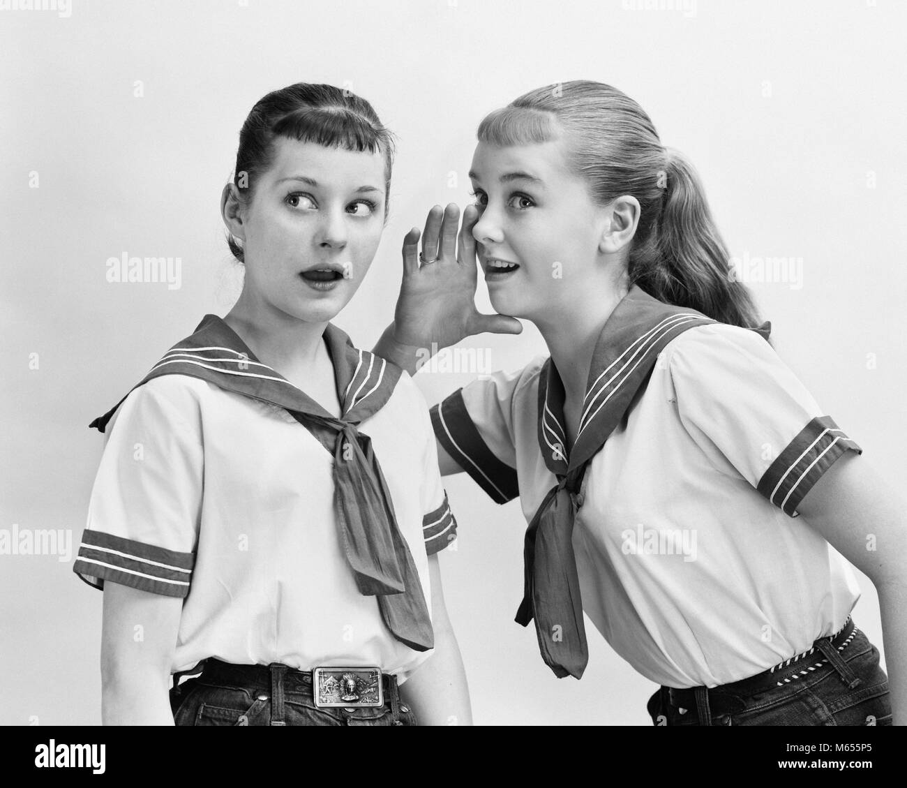 1950s TWO TEENAGED GIRLS WEARING MATCHING NAUTICAL OUTFITS WHISPERING GOSSIPING - asp x16676 CAM001 HARS PLEASED JOY LIFESTYLE FEMALES GOSSIP HOME LIFE COPY SPACE FRIENDSHIP HALF-LENGTH TEENAGE GIRL INDOORS DENIM NAUTICAL GOSSIPING NOSTALGIA TOGETHERNESS 13-15 YEARS 16-17 YEARS BRUNETTE MATCHING JUMPER CHEERFUL DISCOVERY STYLES EXCITEMENT OUTFITS TELLING SMILES JOYFUL FASHIONS HEARING RUMOR TALE TALES TEENAGED BEST FRIEND BLUE JEANS JUVENILES RUMORS SECRETS SPREADING TALKING GOSSIPING TATTLING B&W BANGS BEST FRIENDS BLACK AND WHITE CAUCASIAN ETHNICITY CRACKERJACK DISHING IMPARTING MEAN GIRLS Stock Photo