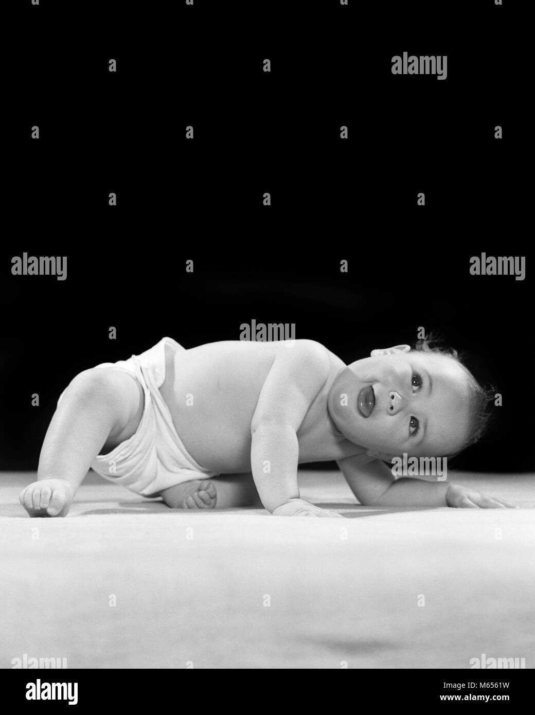 1940s 1950s DIAPERED BABY BENDING DOWN LOOKING UP - b2679 HAR001 HARS JOYFUL BABY BOY 6-12 MONTHS ANGLE JUVENILES LOOKING UP MALES B&W BLACK AND WHITE CAUCASIAN ETHNICITY CLOTH DIAPER DIAPERED LEANING OVER OLD FASHIONED POINT OF VIEW UPSIDE DOWN VANTAGE POINT Stock Photo