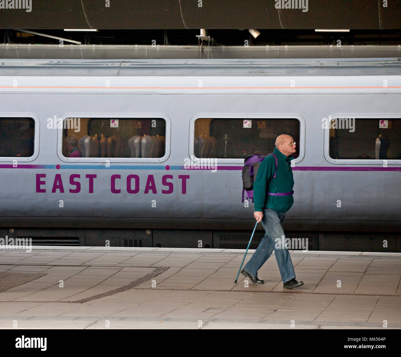 passenger walking past an East coast train at Leeds Railway station during the period when the east coast franchise was publicly run Stock Photo