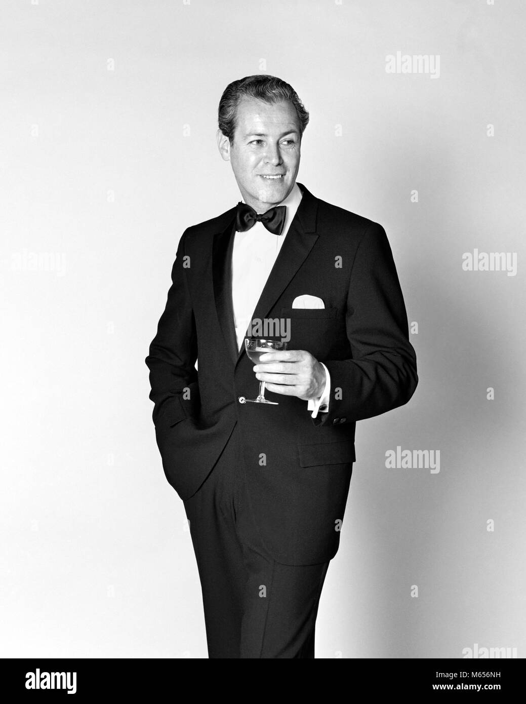 1960s SMILING MAN WEARING TUXEDO HOLDING CHAMPAGNE GLASS - f12257 HAR001 HARS ONE PERSON ONLY LUXURY COPY SPACE HALF-LENGTH INDOORS CONFIDENCE NOSTALGIA 30-35 YEARS 35-40 YEARS SUCCESS TUX HAPPINESS CHEERFUL BEVERAGE LEISURE STYLES RELAXATION SOPHISTICATED RECREATION HANDSOME PRIDE SMILES JOYFUL FASHIONS ATTIRE CALM ATTRACTIVE CONFIDENT MALES MID-ADULT MID-ADULT MAN B&W BLACK AND WHITE BLACK TIE CAUCASIAN ETHNICITY COLLECTED DEBONAIR OLD FASHIONED PERSONS URBANE Stock Photo