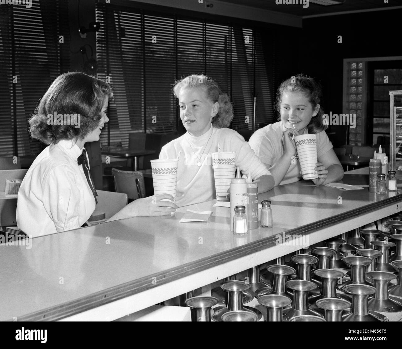 1950s THREE PRE-TEEN GIRLS DRINKING MILKSHAKES SITTING TALKING AT SODA FOUNTAIN COUNTER - f4520 HAR001 HARS TOGETHERNESS 10-12 YEARS 13-15 YEARS HAPPINESS GROWTH MALT MILKSHAKES TEENAGED SMALL GROUP OF PEOPLE JUVENILES PRE-TEEN PRE-TEEN GIRL B&W BLACK AND WHITE CAUCASIAN ETHNICITY DAIRY BAR OLD FASHIONED PERSONS Stock Photo
