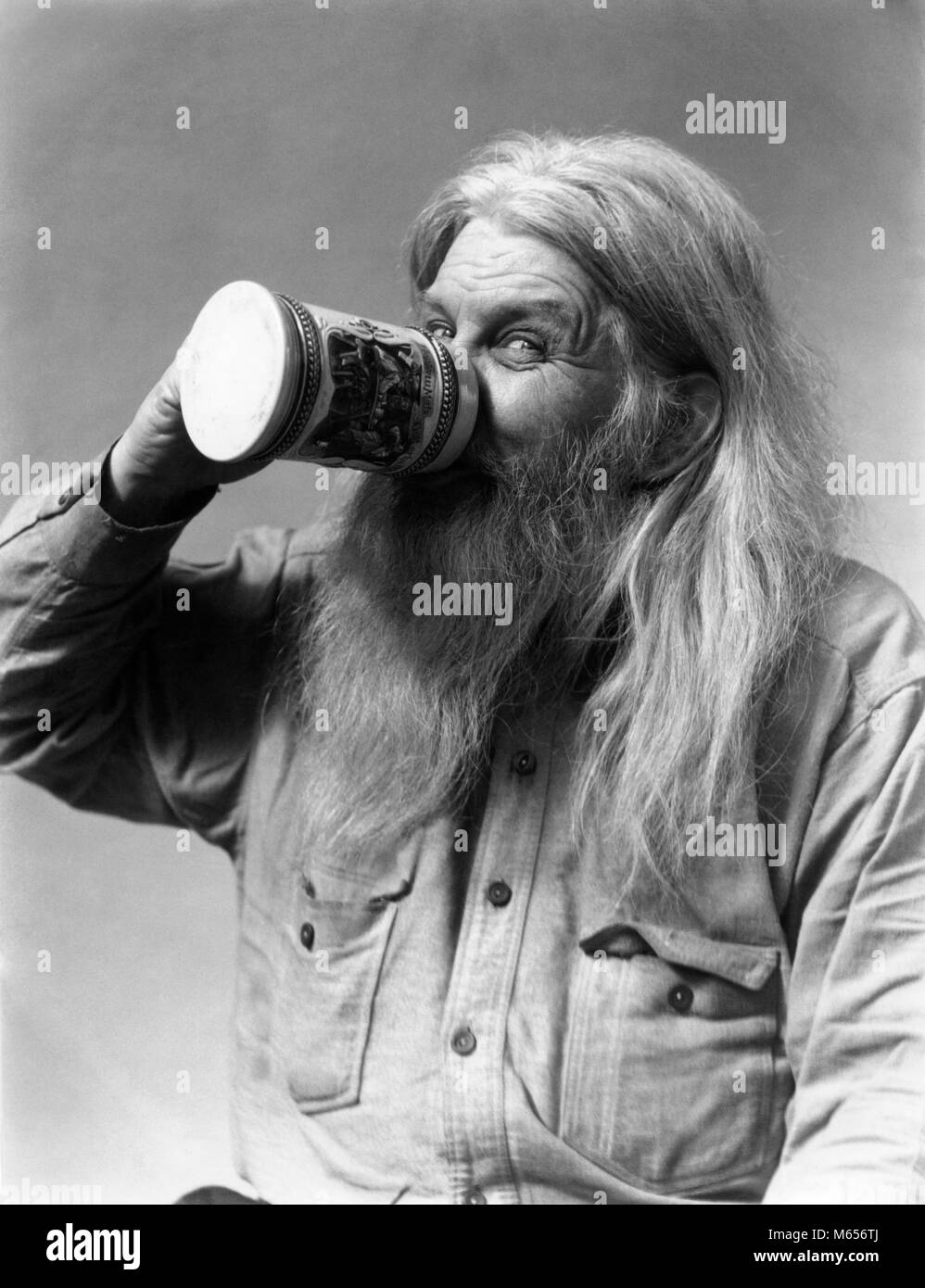 1930s SENIOR MAN CHARACTER WITH SMILING EYES LOOKING AT CAMERA HIRSUTE LONG GRAY BEARD AND HAIR DRINKING BEER FROM STEIN - f7661 HAR001 HARS BEVERAGE FACIAL HAIR BEARDED LONG HAIR HOBO GRAY MALES SCRUFFY B&W BEER STEIN BLACK AND WHITE CAUCASIAN ETHNICITY HAIRY HIRSUTE LOOKING AT CAMERA OLD FASHIONED PERSONS RUMPLED SMILING EYES STEIN UNKEMPT Stock Photo