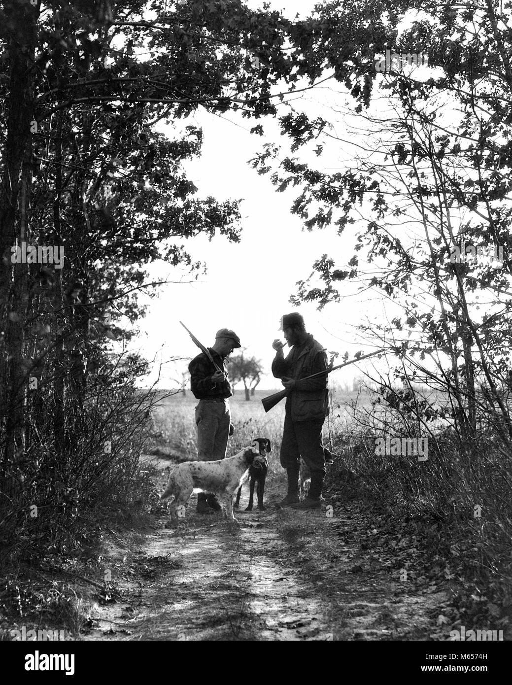 1920s 1930s TWO MEN HUNTERS ANONYMOUS SILHOUETTED WITH DOGS ON COUNTRY LANE - g942 HAR001 HARS SONS JOY LIFESTYLE RURAL FRIENDSHIP FULL-LENGTH ADOLESCENT INSPIRATION CARING ANIMALS HUNTER SPIRITUALITY CONFIDENCE NOSTALGIA FATHERS 20-25 YEARS 25-30 YEARS 30-35 YEARS FREEDOM TWO ANIMALS MAMMALS ADVENTURE LEISURE RELAXATION SILHOUETTED CANINES DADS RECREATION POOCH CONNECTION TEENAGED ANONYMOUS CANINE FIREARM FIREARMS HUNTERS JUVENILES MALES MAMMAL MID-ADULT MID-ADULT MAN SHOTGUNS YOUNG ADULT MAN B&W BLACK AND WHITE COUNTRY LANE OLD FASHIONED PERSONS Stock Photo
