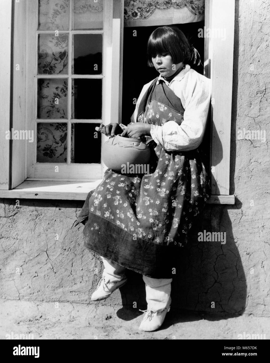 1930s NATIVE AMERICAN WOMAN SITTING ON WINDOWSILL DECORATING POTTERY WEARING TYPICAL COSTUME SAN ILDEFONSO PUEBLO NEW MEXICO USA - i1247 HAR001 HARS ARTIST SPIRITUALITY CONFIDENCE NOSTALGIA POTTERY NORTH AMERICA 20-25 YEARS 25-30 YEARS NORTH AMERICAN SINGLE OBJECT STRENGTH KNOWLEDGE WINDOWSILL 18-19 YEARS INNOVATION PRIDE AUTHORITY CREATIVITY NATIVE AMERICAN PUEBLO SAN ILDEFONSO NEW MEXICO TYPICAL YOUNG ADULT WOMAN B&W BLACK AND WHITE CRAFTS PERSON INDIGENOUS NATIVE DRESS NM OCCUPATIONS OLD FASHIONED PERSONS POTTER Stock Photo