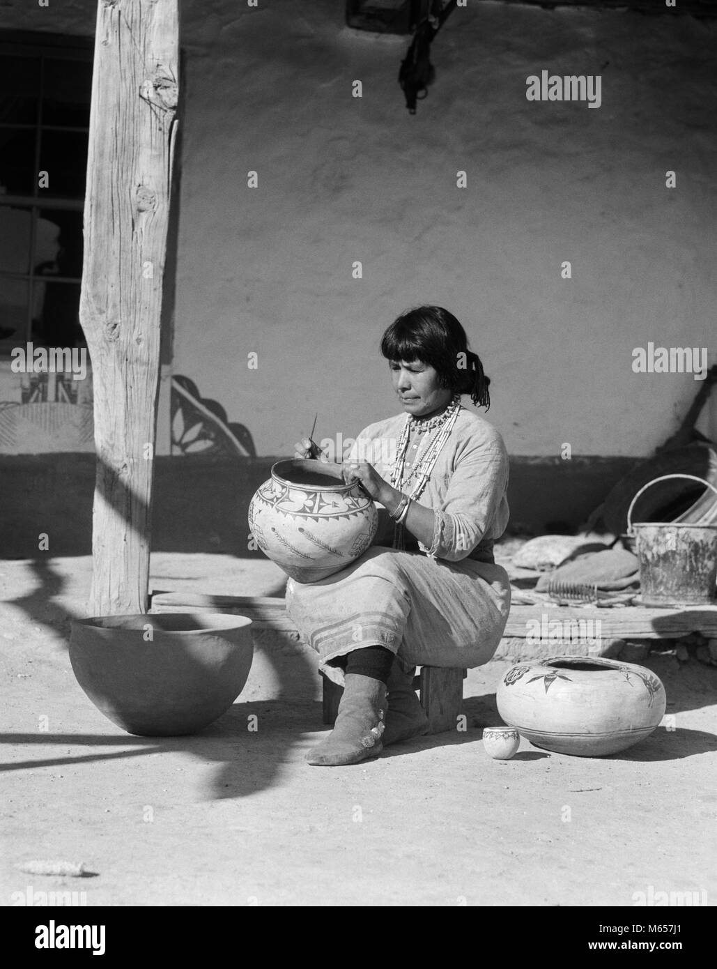 1930s NATIVE AMERICAN INDIAN WOMAN DECORATING POTTERY COCHITI PUEBLO NEW MEXICO USA - i1492 HAR001 HARS MID-ADULT MID-ADULT WOMAN NATIVE AMERICANS NEW MEXICO B&W BLACK AND WHITE INDIGENOUS OCCUPATIONS OLD FASHIONED PERSONS POTTER SOUTHWESTERN Stock Photo