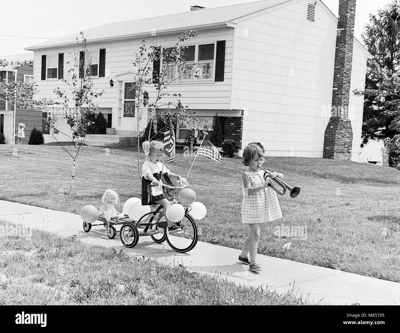 1960s GIRL WITH BUGLE LEADING SISTER ON TRICYCLE DECORATED WITH BALLOONS AMERICAN FLAGS FOR JULY 4TH HOLIDAY SIDEWALK PARADE - j12200 HAR001 HARS FEMALES 4TH HEALTHINESS HOME LIFE COPY SPACE PEOPLE CHILDREN FRIENDSHIP FULL-LENGTH FOURTH SIBLINGS AMERICANA DECORATED SISTERS NOSTALGIA LEADING TOGETHERNESS 3-4 YEARS FREEDOM SUCCESS 5-6 YEARS HAPPINESS TRICYCLE NEIGHBORHOOD EXCITEMENT LEADERSHIP RECREATION PRIDE SUPPORT MARCH SIBLING MUSICAL INSTRUMENT PATRIOTIC WAGONS BUGLE JUVENILES AMERICAN FLAG B&W BLACK AND WHITE BUGLES CAUCASIAN ETHNICITY JULY 4TH MEMORIAL DAY OLD FASHIONED PARADES TRICYCLES Stock Photo